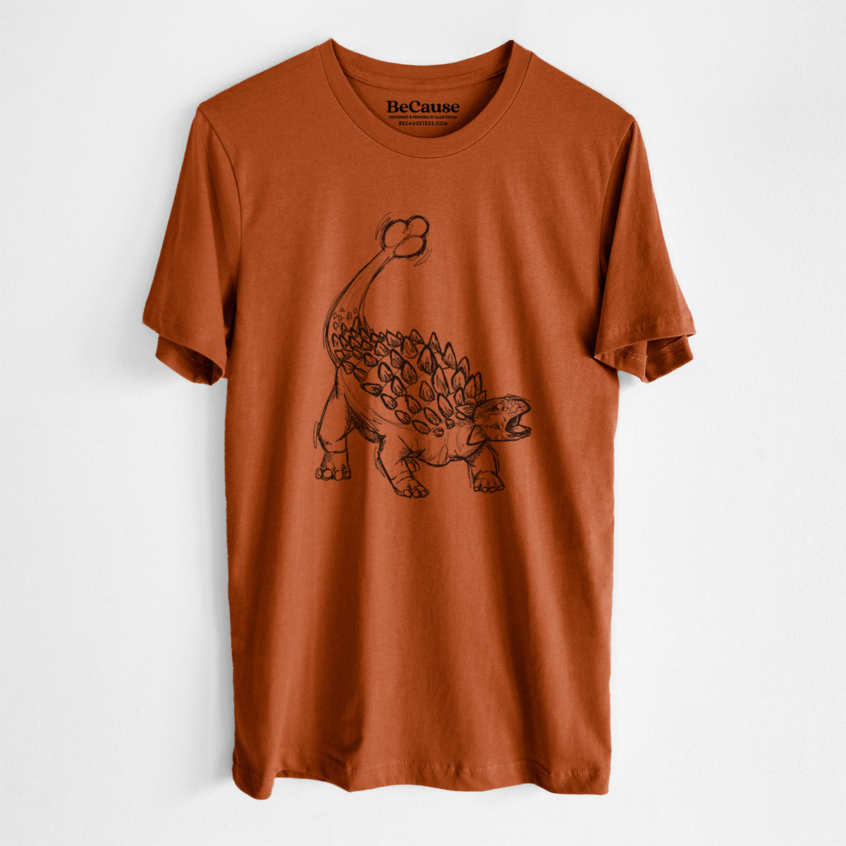 Autumn lightweight cotton t-shirt laid flat, printed with a black ink illustration of an Ankylosaurus with its club tail raised.
