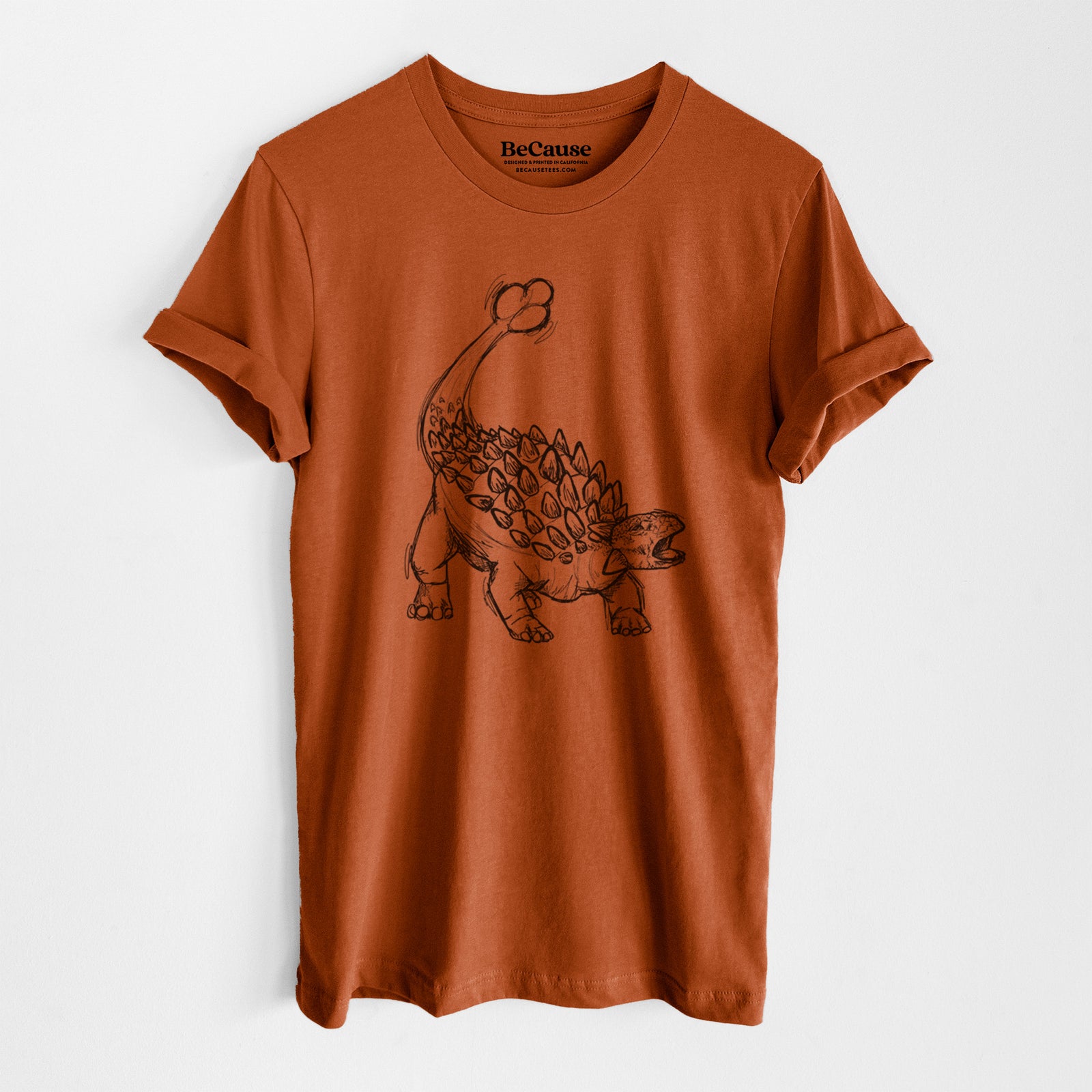 Autumn lightweight cotton t-shirt laid flat, printed with a black ink illustration of an Ankylosaurus with its club tail raised.