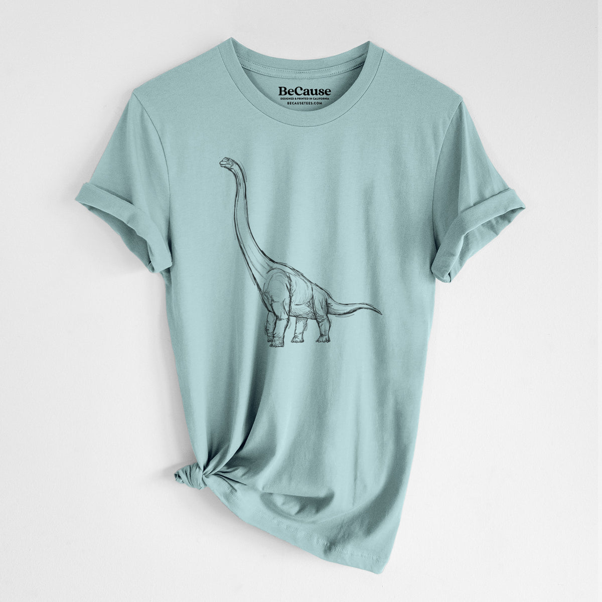 Dusty blue lightweight cotton t-shirt laid flat with the sleeves rolled, printed with a black ink illustration of a long-necked Apatosaurus walking.