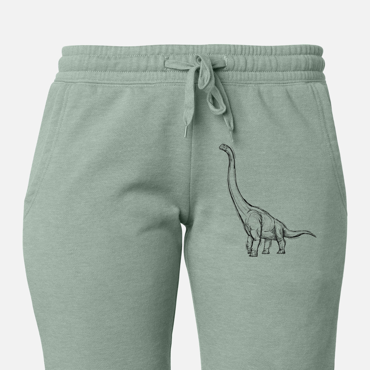 Front of sage green Cali Wave sweatpants, printed with a black ink illustration of a long-necked Apatosaurus walking on the leg.