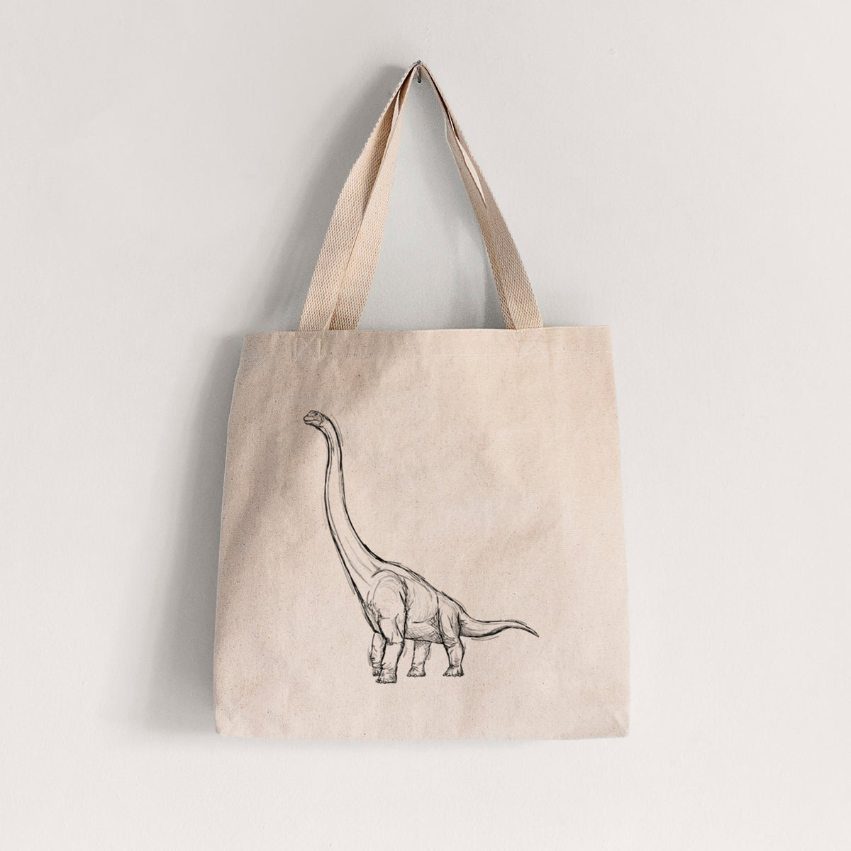 Natural canvas tote bag printed with a black ink illustration of a long-necked Apatosaurus walking.