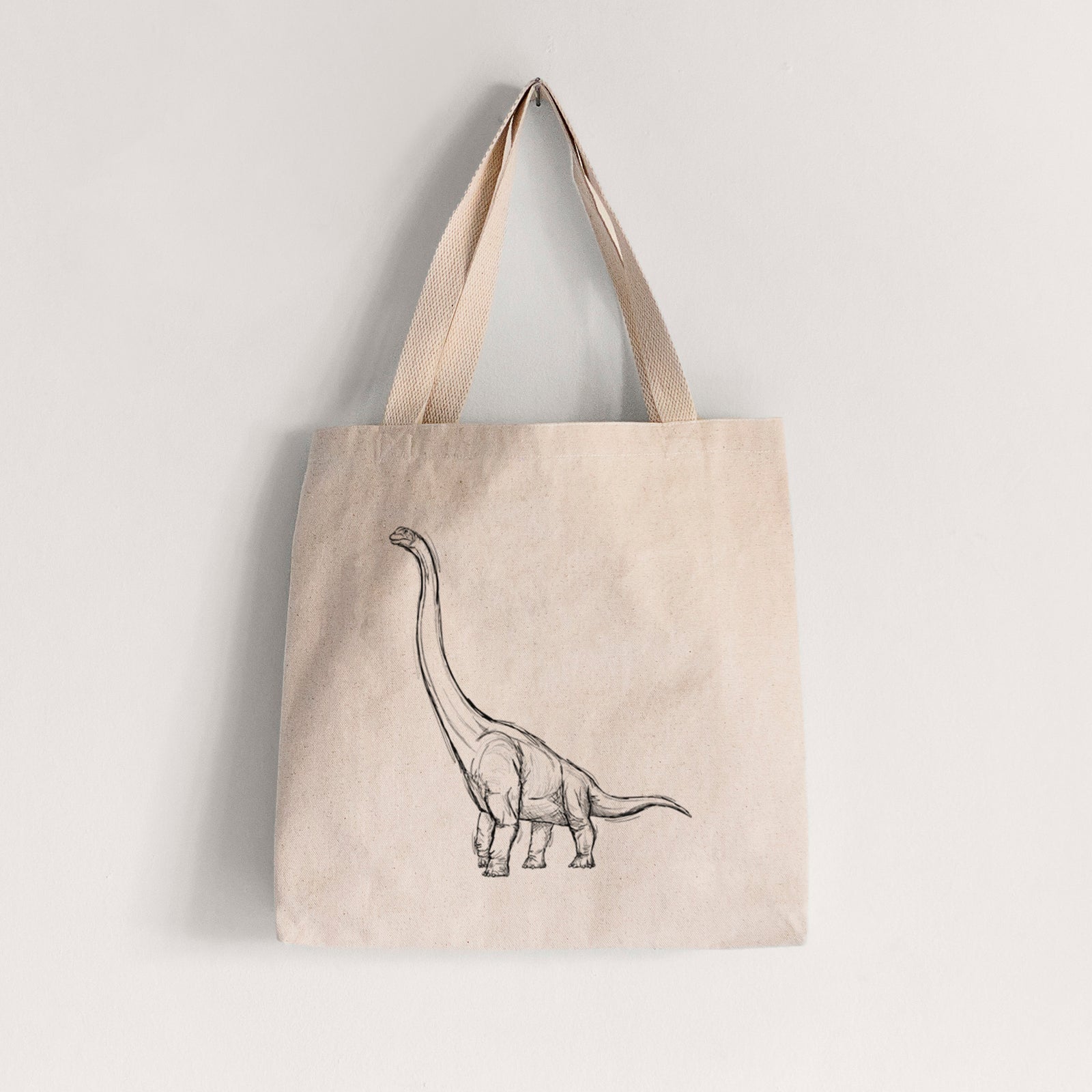 Natural canvas tote bag printed with a black ink illustration of a long-necked Apatosaurus walking.