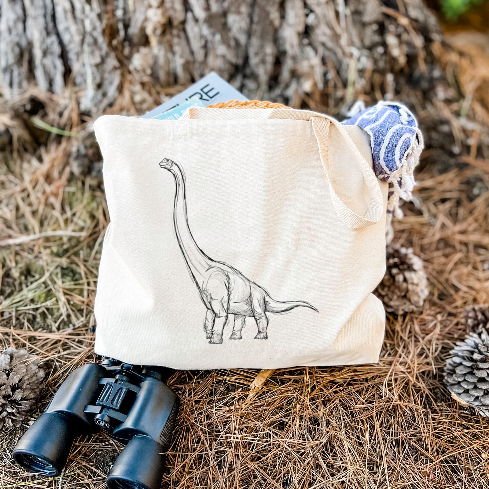 Natural canvas tote bag printed with a black ink illustration of a long-necked Apatosaurus walking.