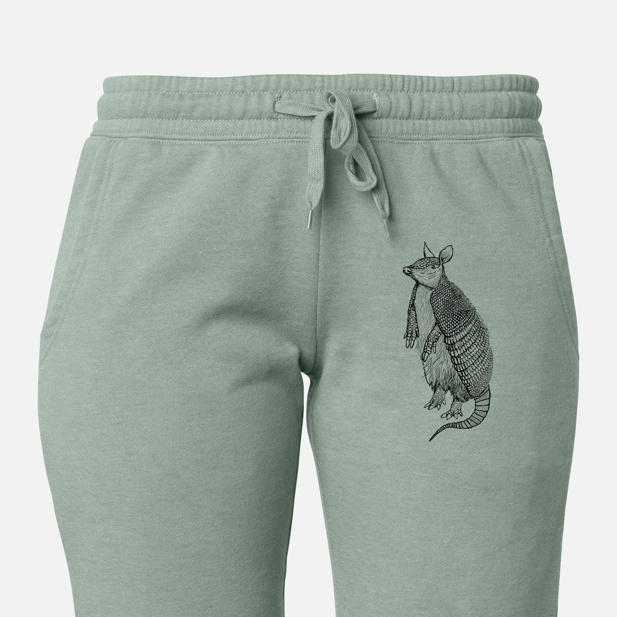 Front of sage green Cali Wave sweatpants, printed with a black ink illustration of a nine-banded armadillo standing upright on the leg.