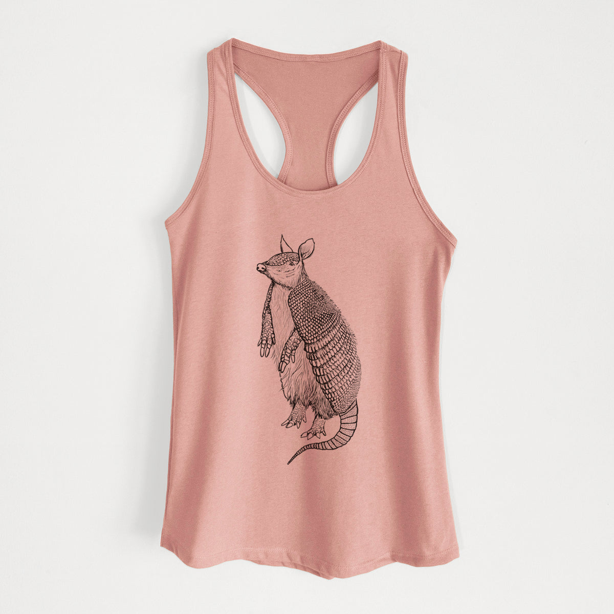 Desert pink women's racerback tank top laid flat, printed with a black ink illustration of a nine-banded armadillo standing upright.