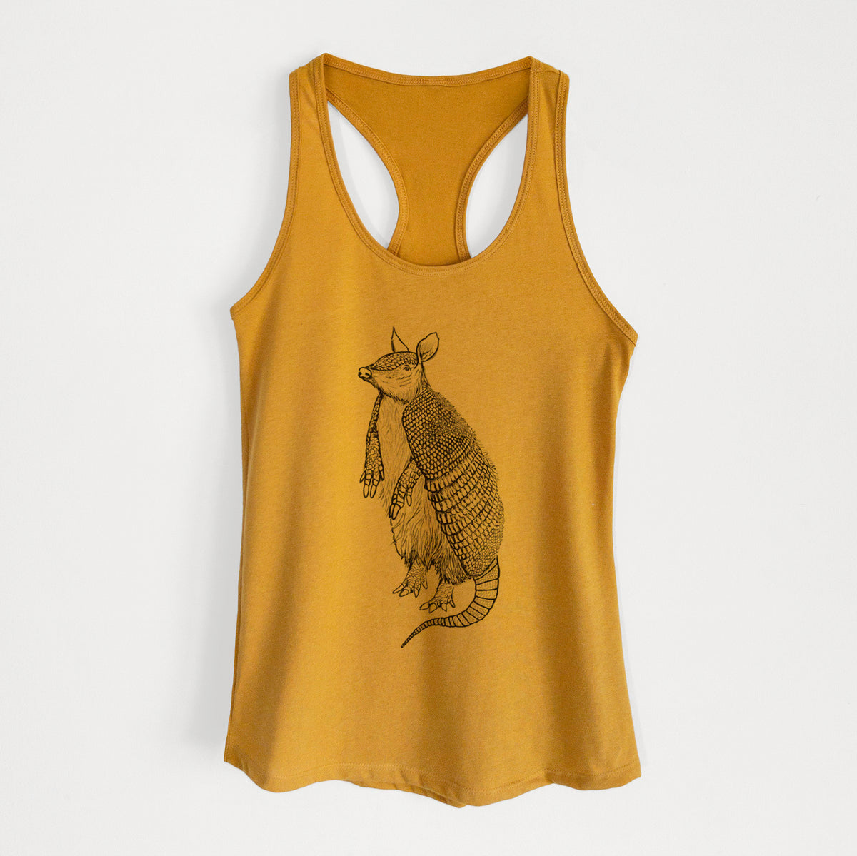 Gold women's racerback tank top laid flat, printed with a black ink illustration of a nine-banded armadillo standing upright.