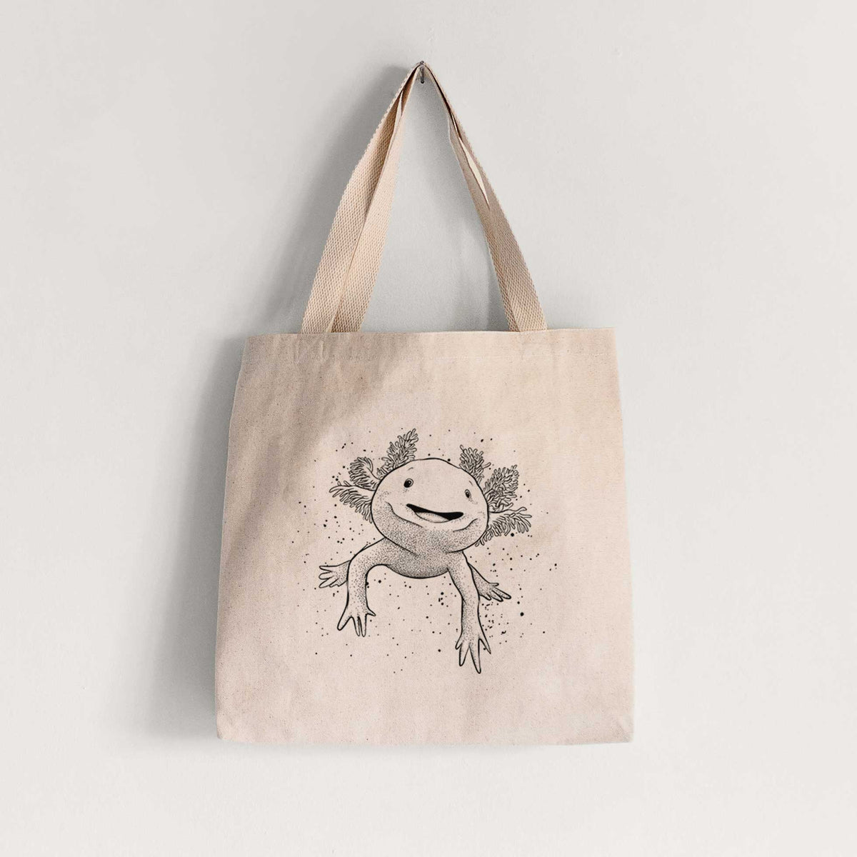 Natural canvas tote bag printed with a black ink illustration of a smiling axolotl with feathery gills.