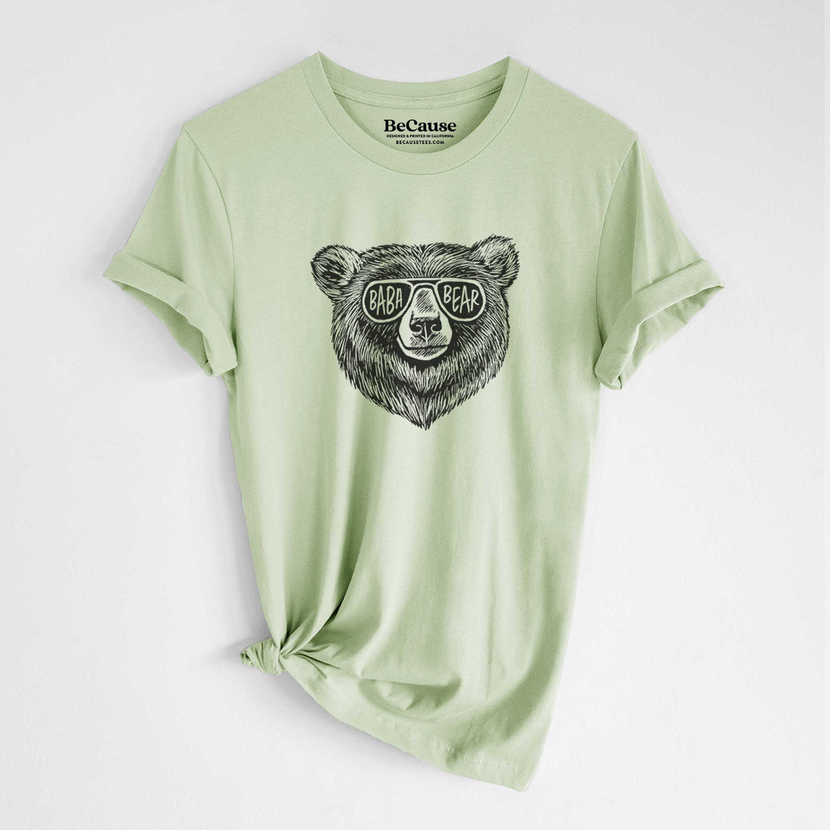 Spring green lightweight cotton t-shirt laid flat with the sleeves rolled, printed with a black ink bear's face wearing sunglasses that read Baba Bear.