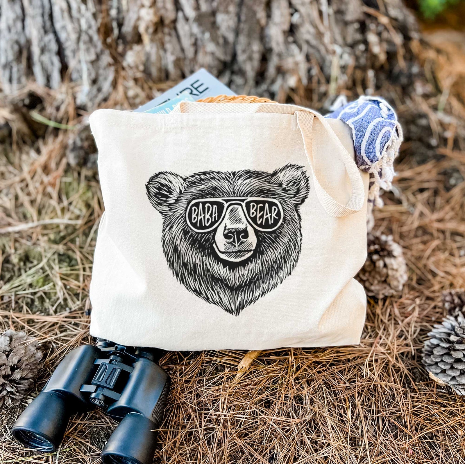 Natural canvas tote bag printed with a black ink bear's face wearing sunglasses that read Baba Bear.