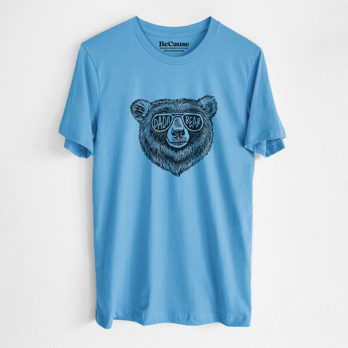 Ocean blue lightweight cotton t-shirt laid flat, printed with a black ink bear's face wearing sunglasses that read Dada Bear.