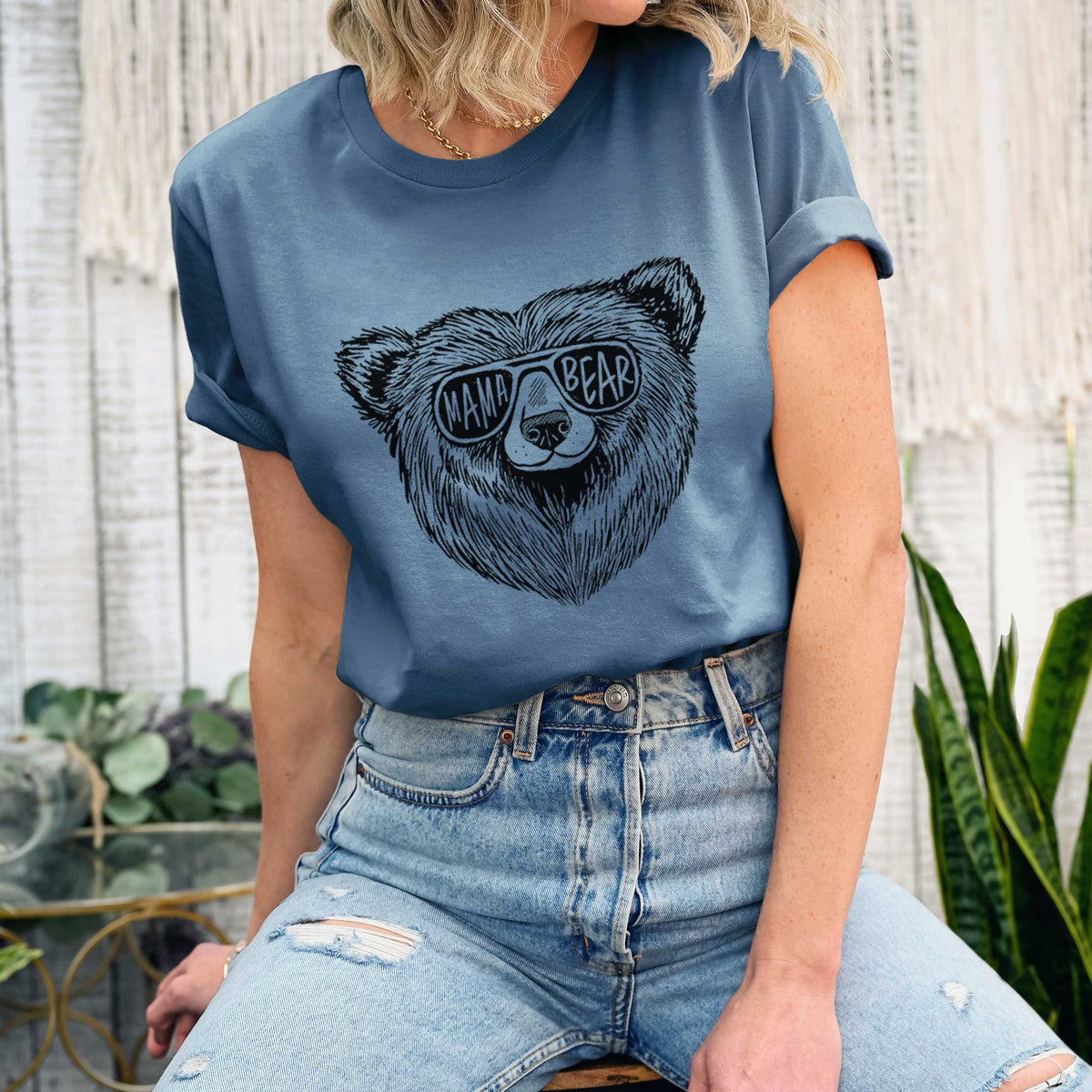 Woman wearing a steel blue lightweight cotton t-shirt printed with a black ink bear's face wearing sunglasses that read Mama Bear.