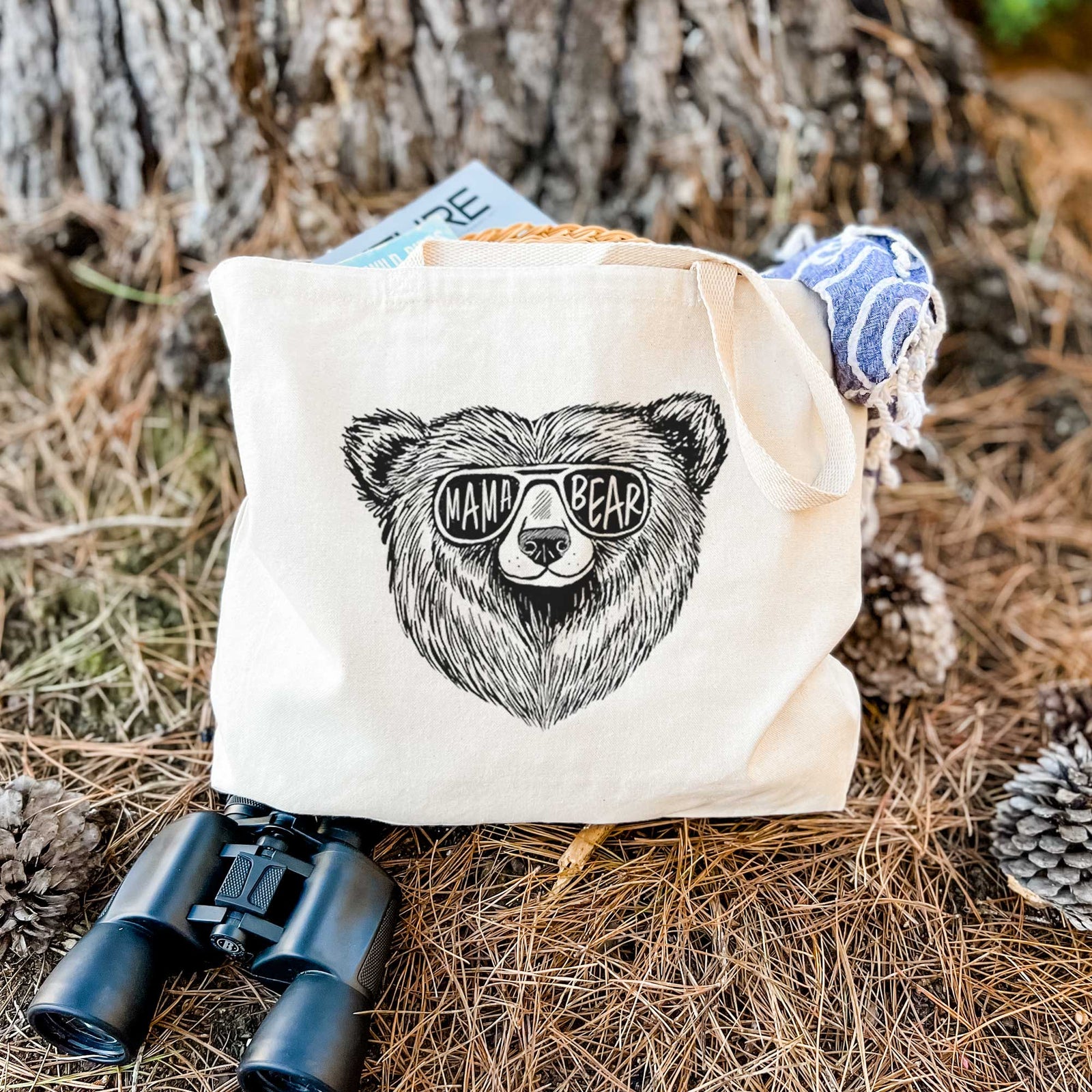 Natural canvas tote bag printed with a black ink bear's face wearing sunglasses that read Mama Bear.