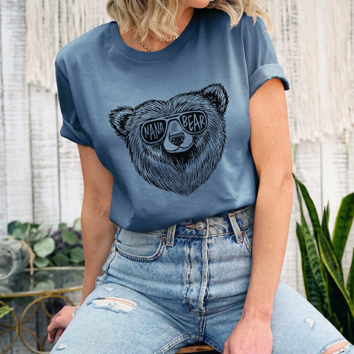 Woman wearing a steel blue lightweight cotton t-shirt printed with a black ink bear's face wearing sunglasses that read Nana Bear.