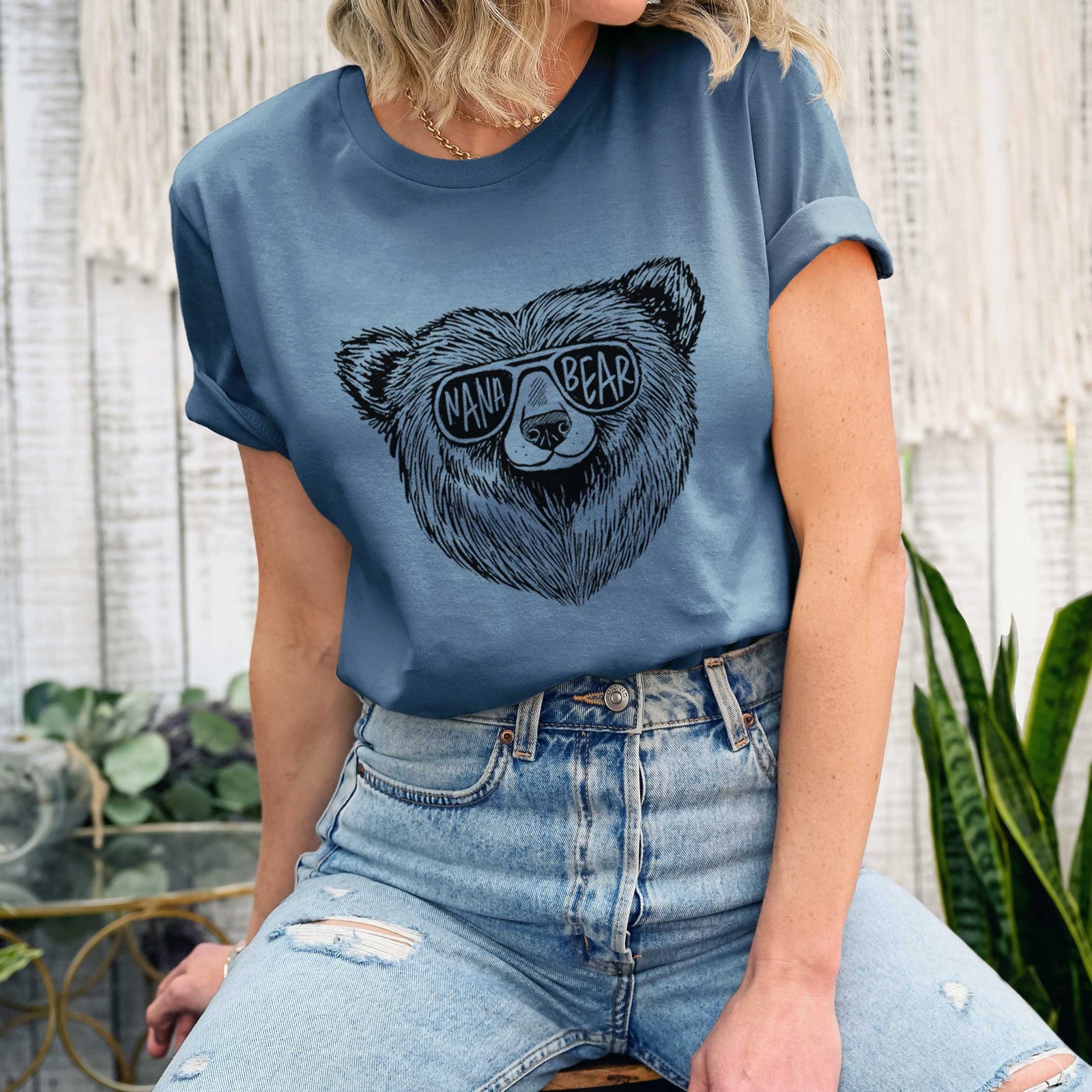 Mauve pink lightweight cotton t-shirt laid flat with the sleeves rolled, printed with a black ink bear's face wearing sunglasses that read Nana Bear.