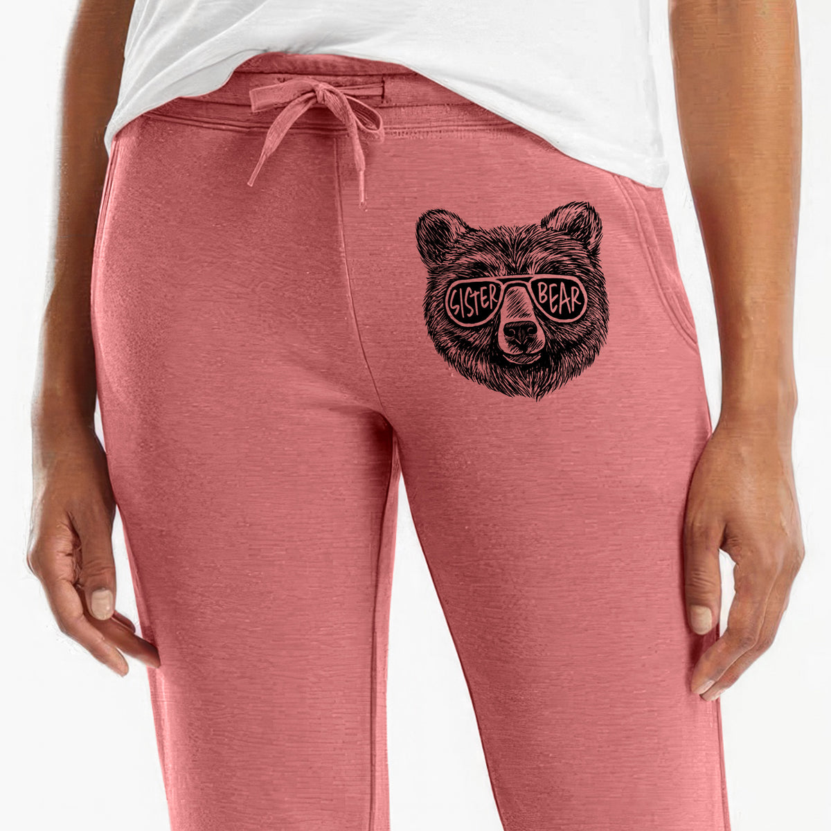 Front of dusty rose Cali Wave sweatpants, printed with a black ink bear's face wearing sunglasses that read Sister Bear on the leg.