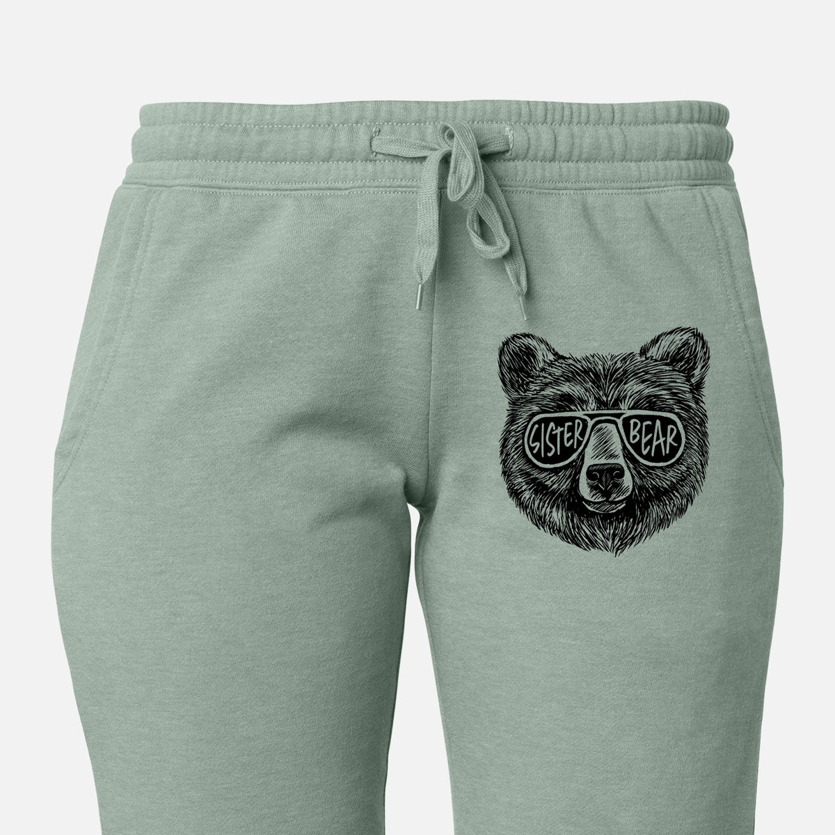 Front of sage green Cali Wave sweatpants, printed with a black ink bear's face wearing sunglasses that read Sister Bear on the leg.