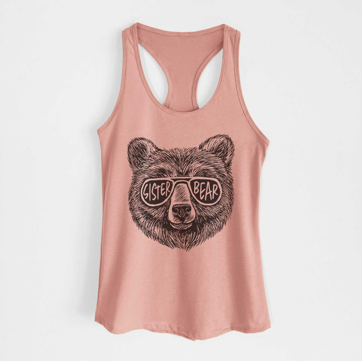 Desert pink women's racerback tank top laid flat, printed with a black ink bear's face wearing sunglasses that read Sister Bear.