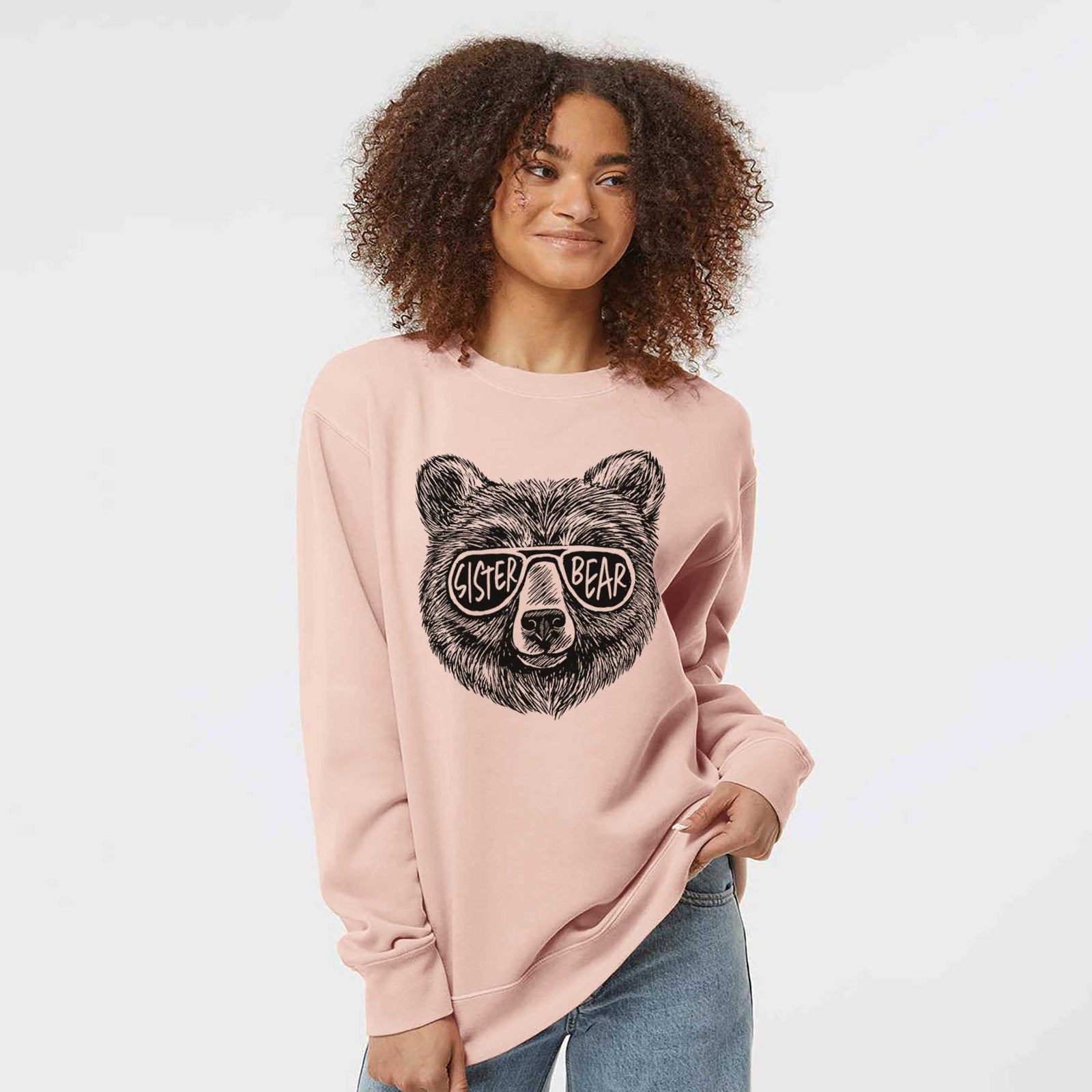 Sage green pigment dyed crewneck sweatshirt laid flat, printed with a black ink bear's face wearing sunglasses that read Sister Bear.