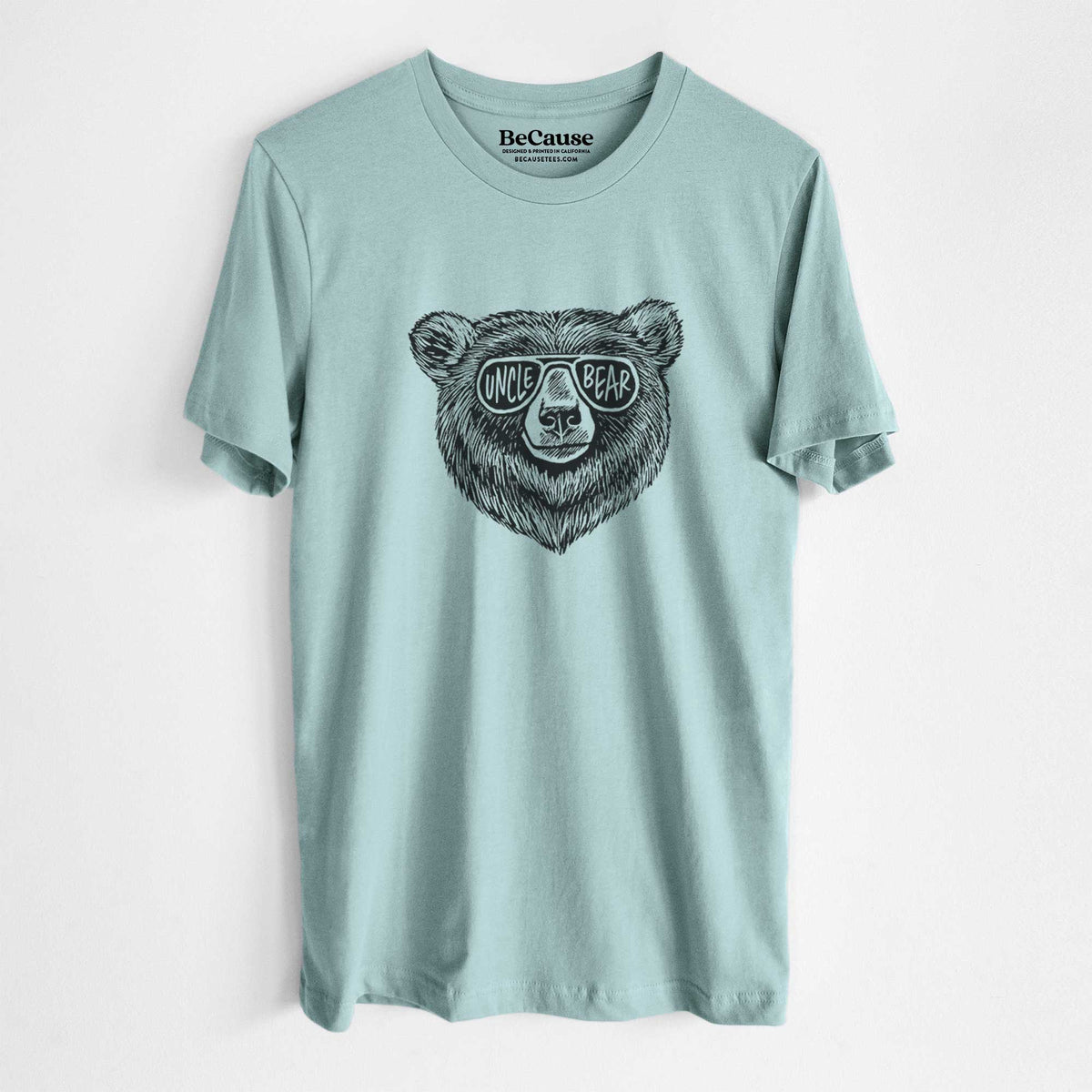 Dusty blue lightweight cotton t-shirt laid flat, printed with a black ink bear's face wearing sunglasses that read Uncle Bear.