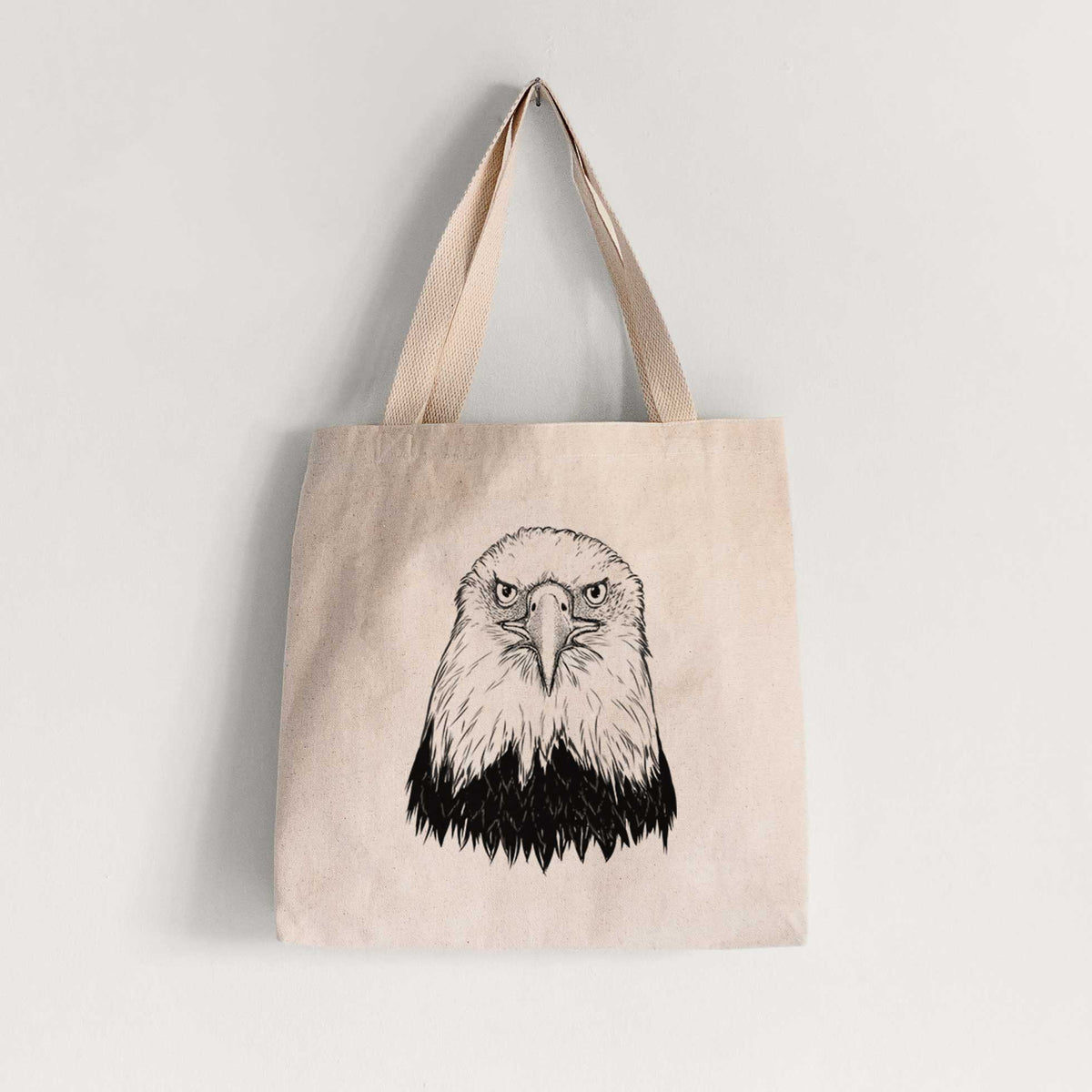Natural canvas tote bag printed with a detailed black ink portrait of a bald eagle facing forward.