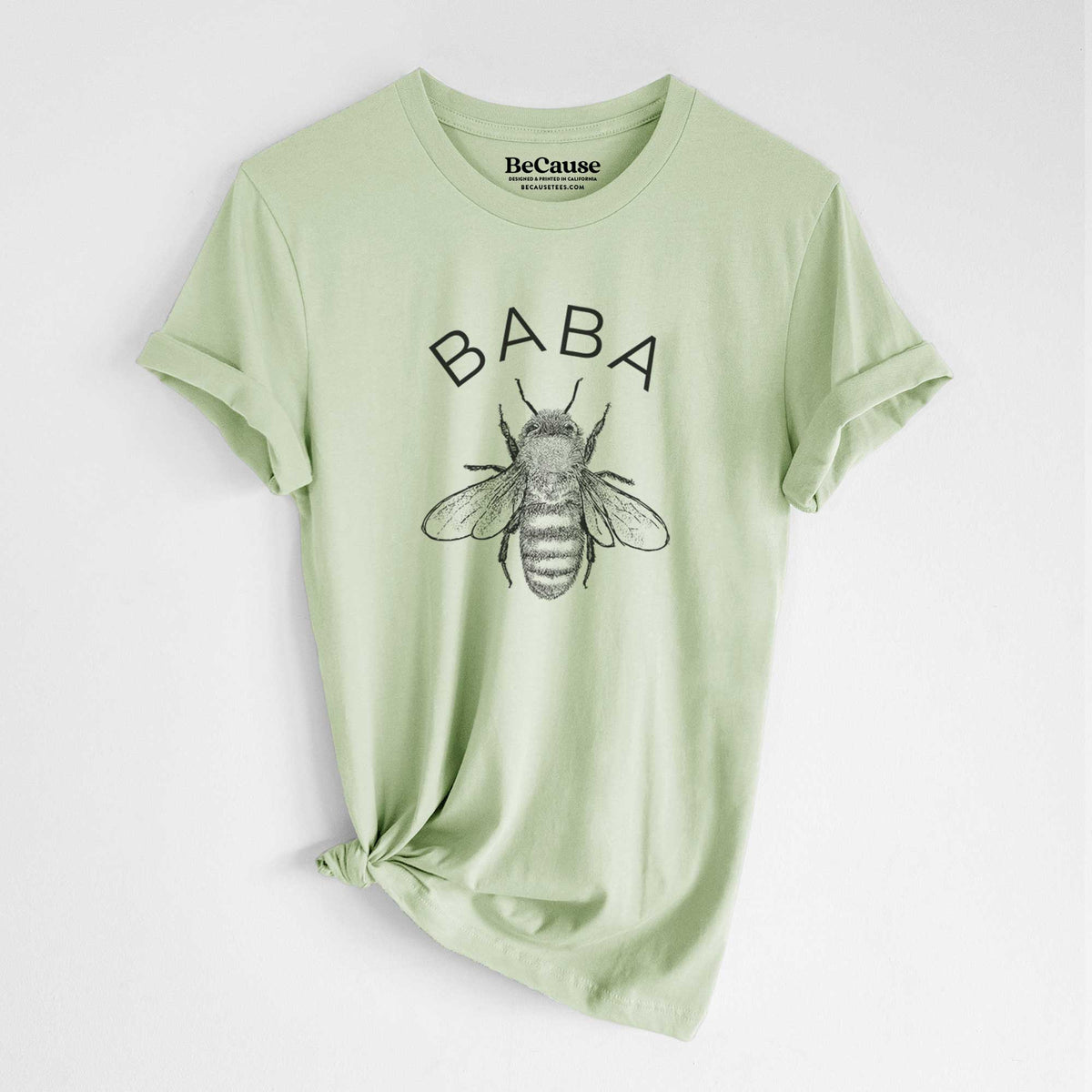 Spring green lightweight cotton t-shirt laid flat with the sleeves rolled, printed with a black ink honey bee beneath the word Baba.