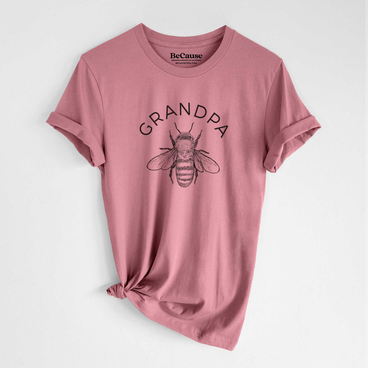 Mauve pink lightweight cotton t-shirt laid flat with the sleeves rolled, printed with a black ink honey bee beneath the word Grandpa.