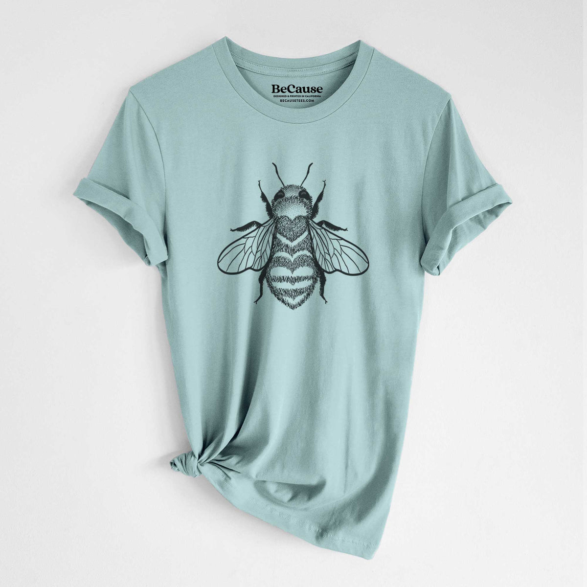 Dusty blue lightweight cotton t-shirt laid flat with the sleeves rolled, printed with a black ink bee with a heart pattern on its body.