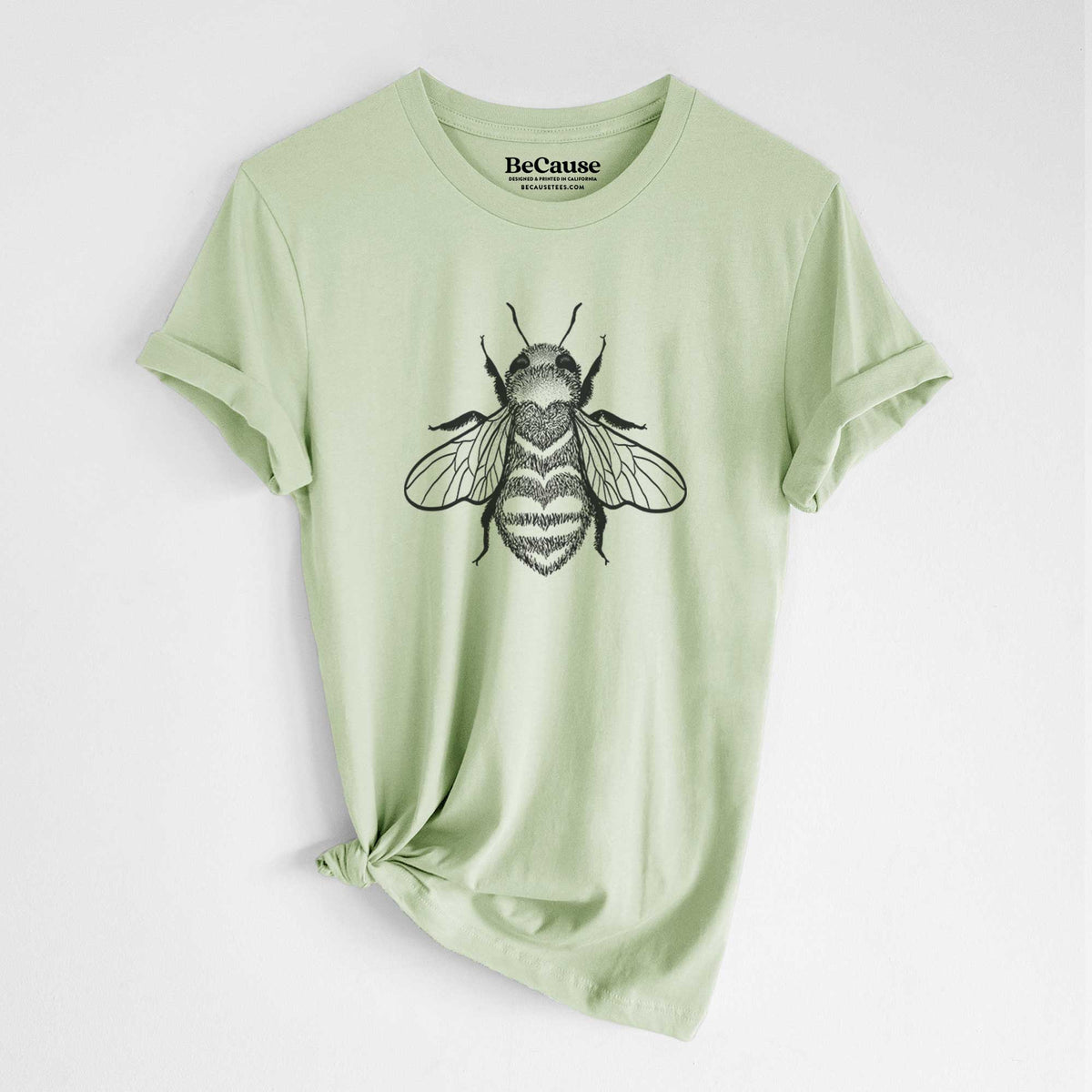 Spring green lightweight cotton t-shirt laid flat with the sleeves rolled, printed with a black ink bee with a heart pattern on its body.