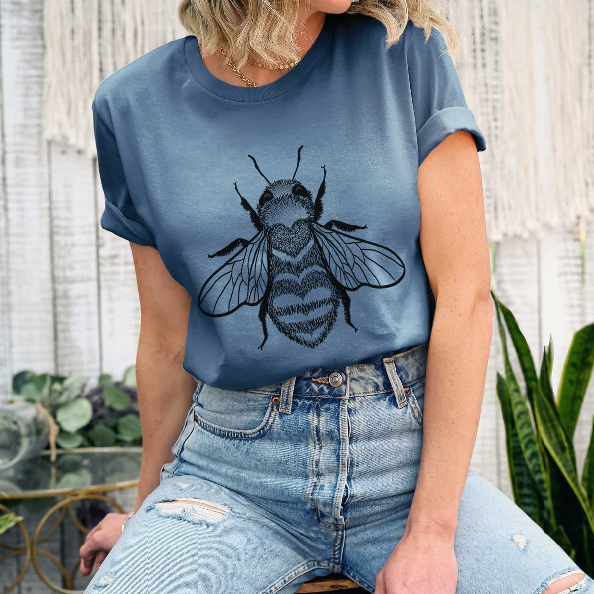 Woman wearing a steel blue lightweight cotton t-shirt printed with a black ink bee with a heart pattern on its body.