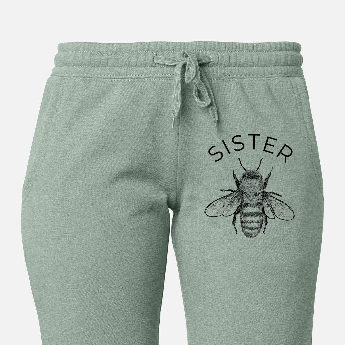 Front of sage green Cali Wave sweatpants, printed with a black ink honey bee beneath the word Sister on the leg.