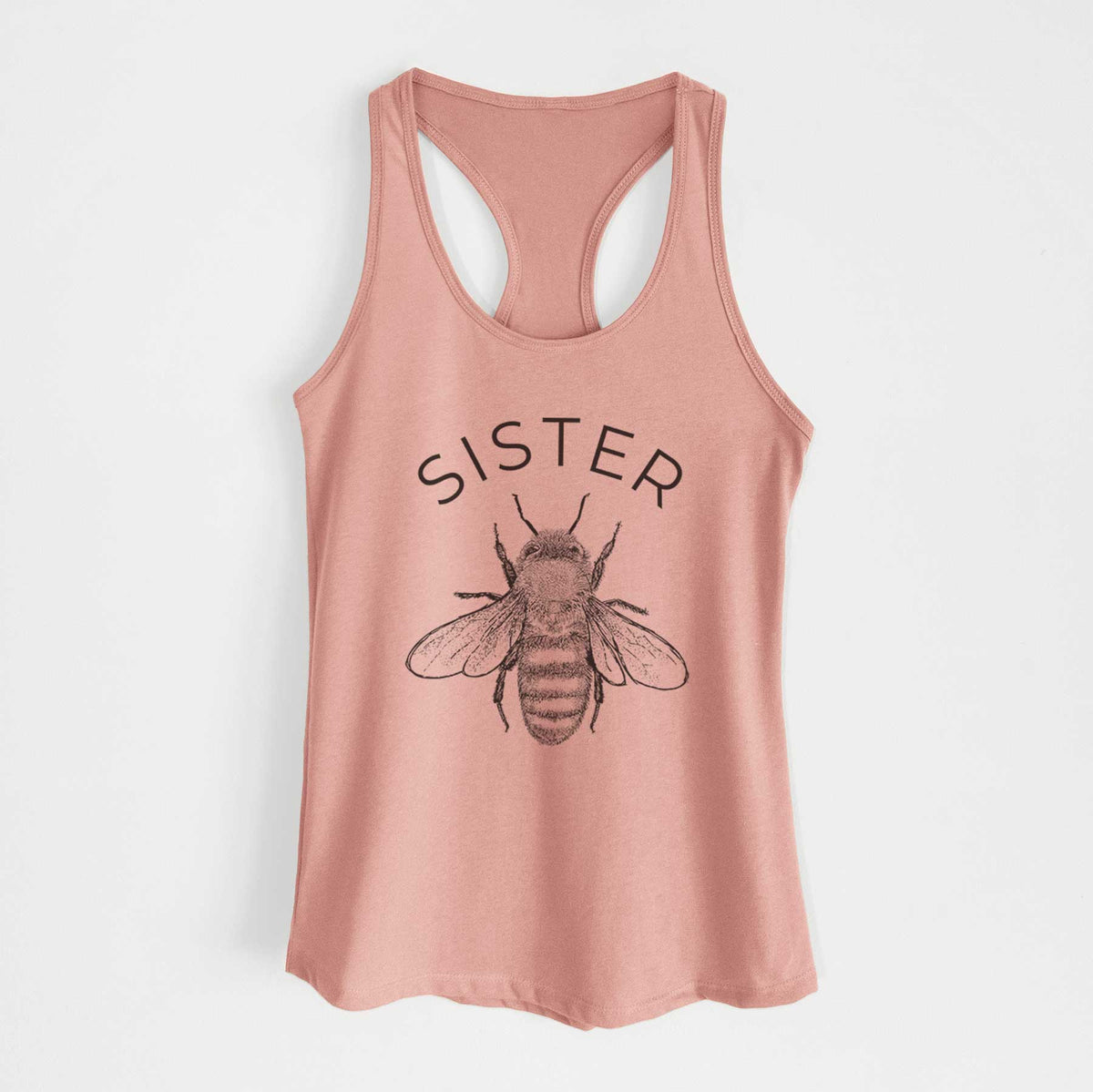 Desert pink women's racerback tank top laid flat, printed with a black ink honey bee beneath the word Sister.