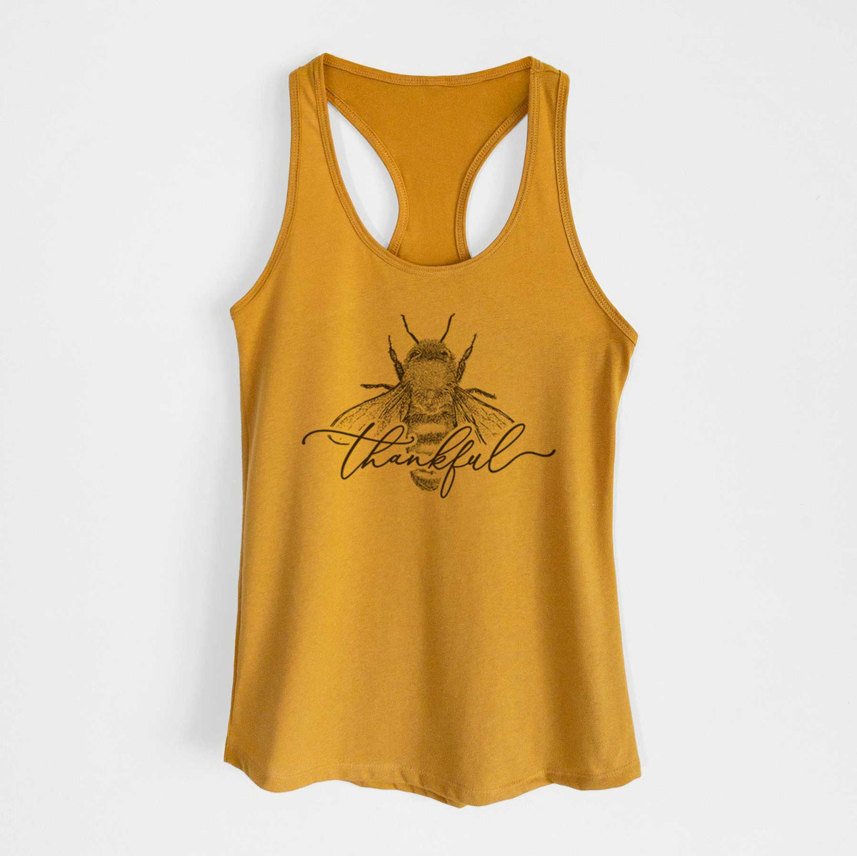 Gold women's racerback tank top laid flat, printed with a black ink bee with the word thankful written in script across it.