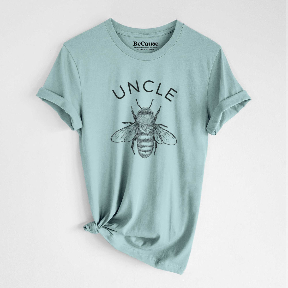 Dusty blue lightweight cotton t-shirt laid flat with the sleeves rolled, printed with a black ink honey bee beneath the word Uncle.