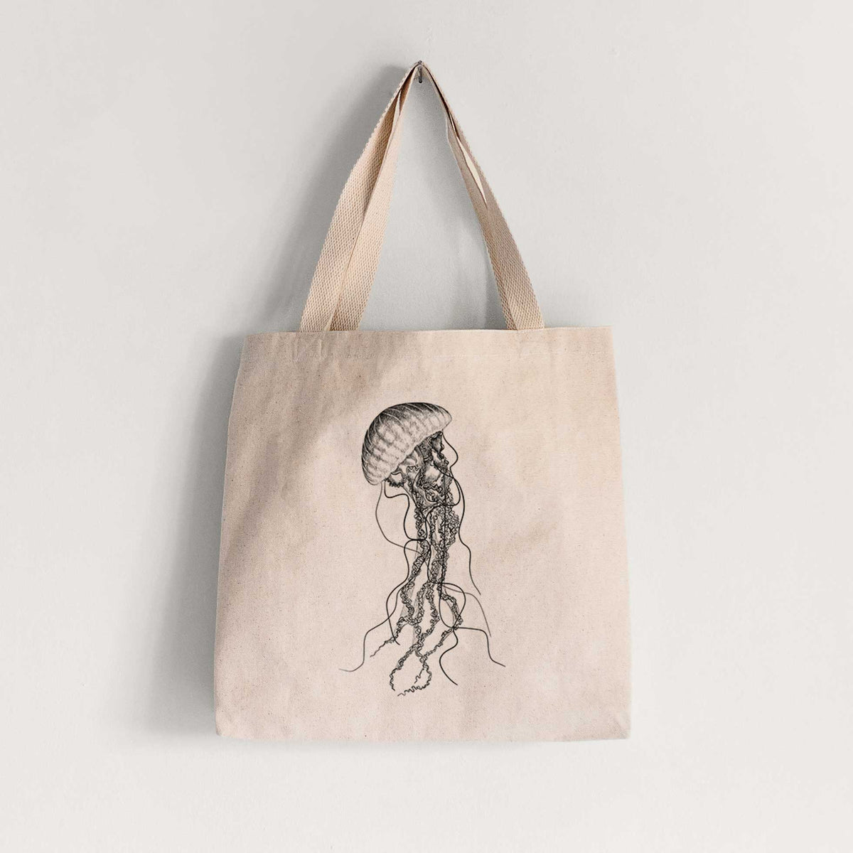 Natural canvas tote bag printed with a black ink illustration of a black sea nettle jellyfish with long trailing tentacles.