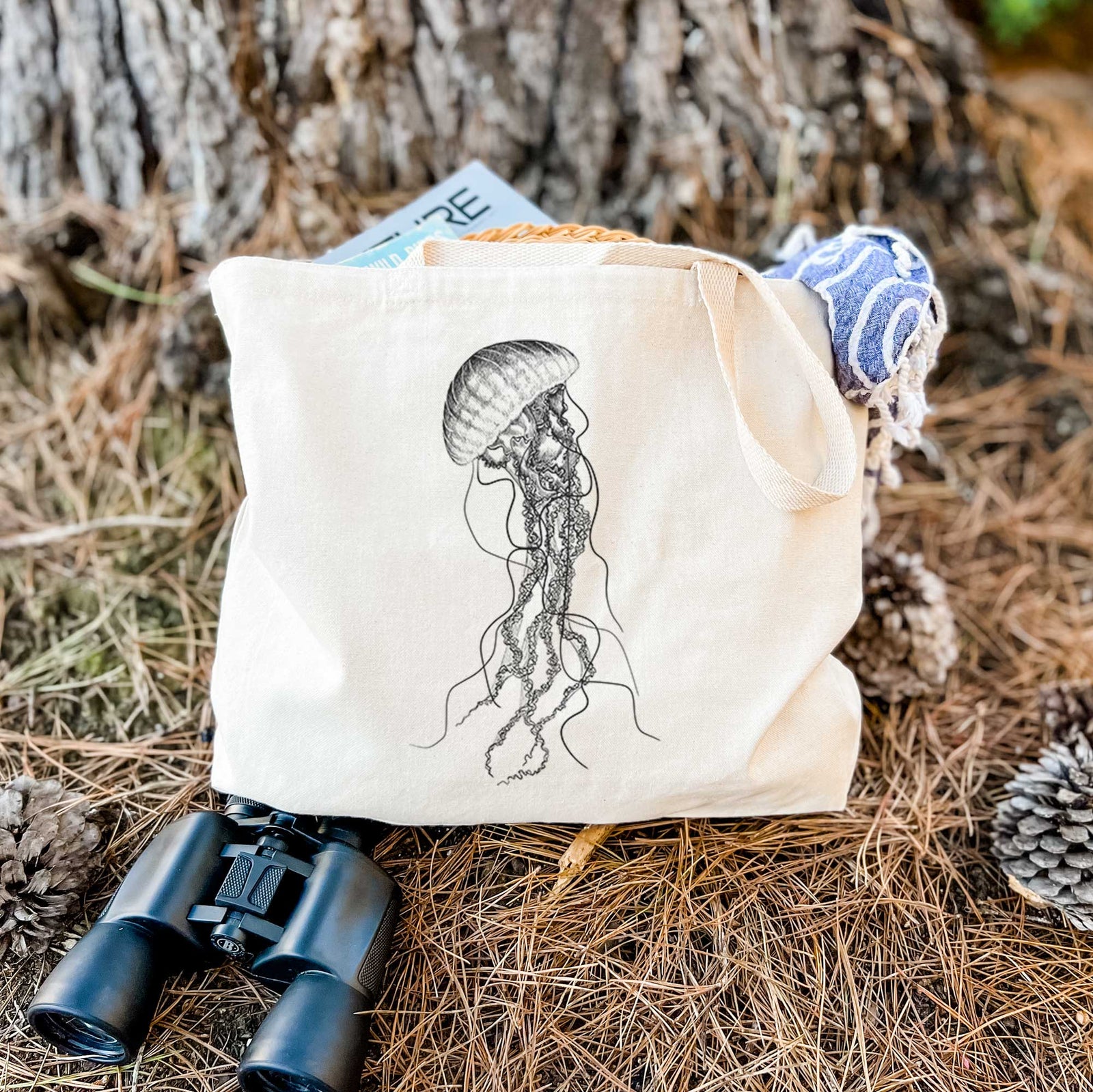 Natural canvas tote bag printed with a black ink illustration of a black sea nettle jellyfish with long trailing tentacles.