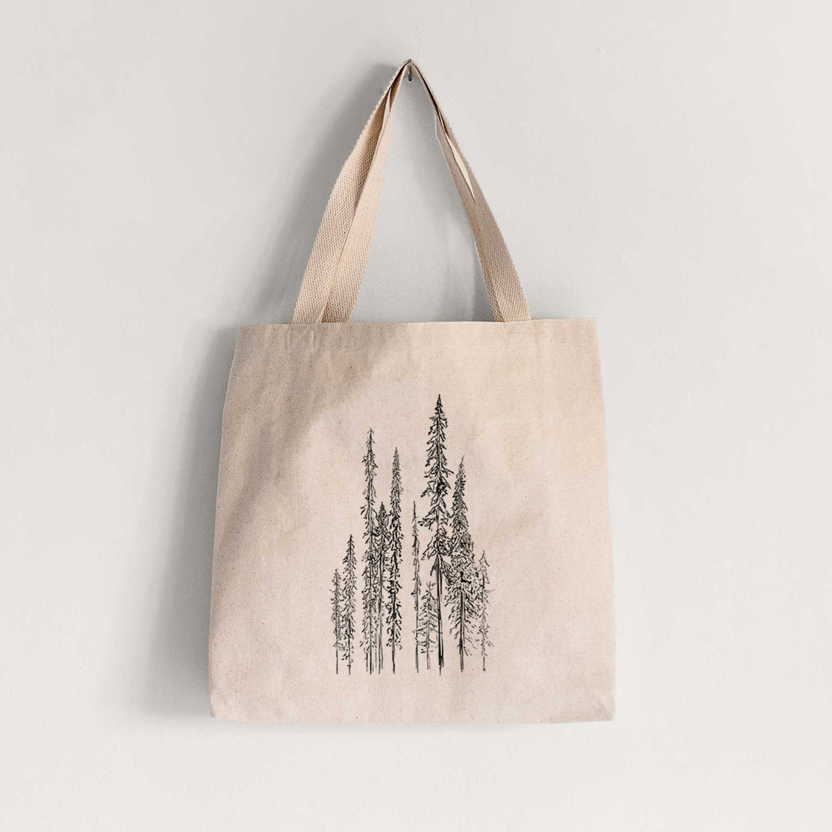 Natural canvas tote bag printed with a black ink illustration of a stand of tall, narrow black spruce trees.