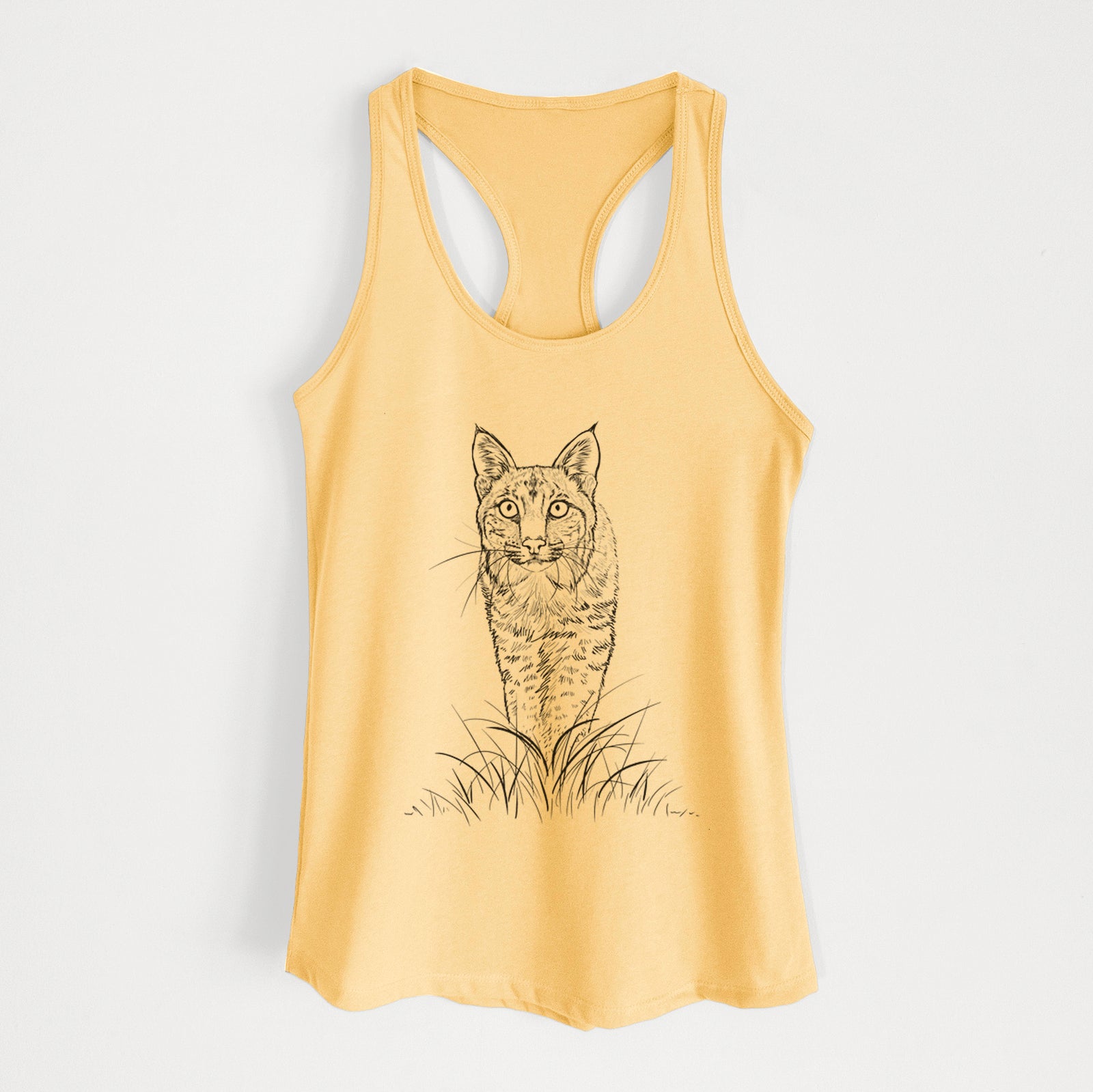 Banana cream women's racerback tank top laid flat, printed with a black ink illustration of a bobcat standing in tall grass, facing forward.