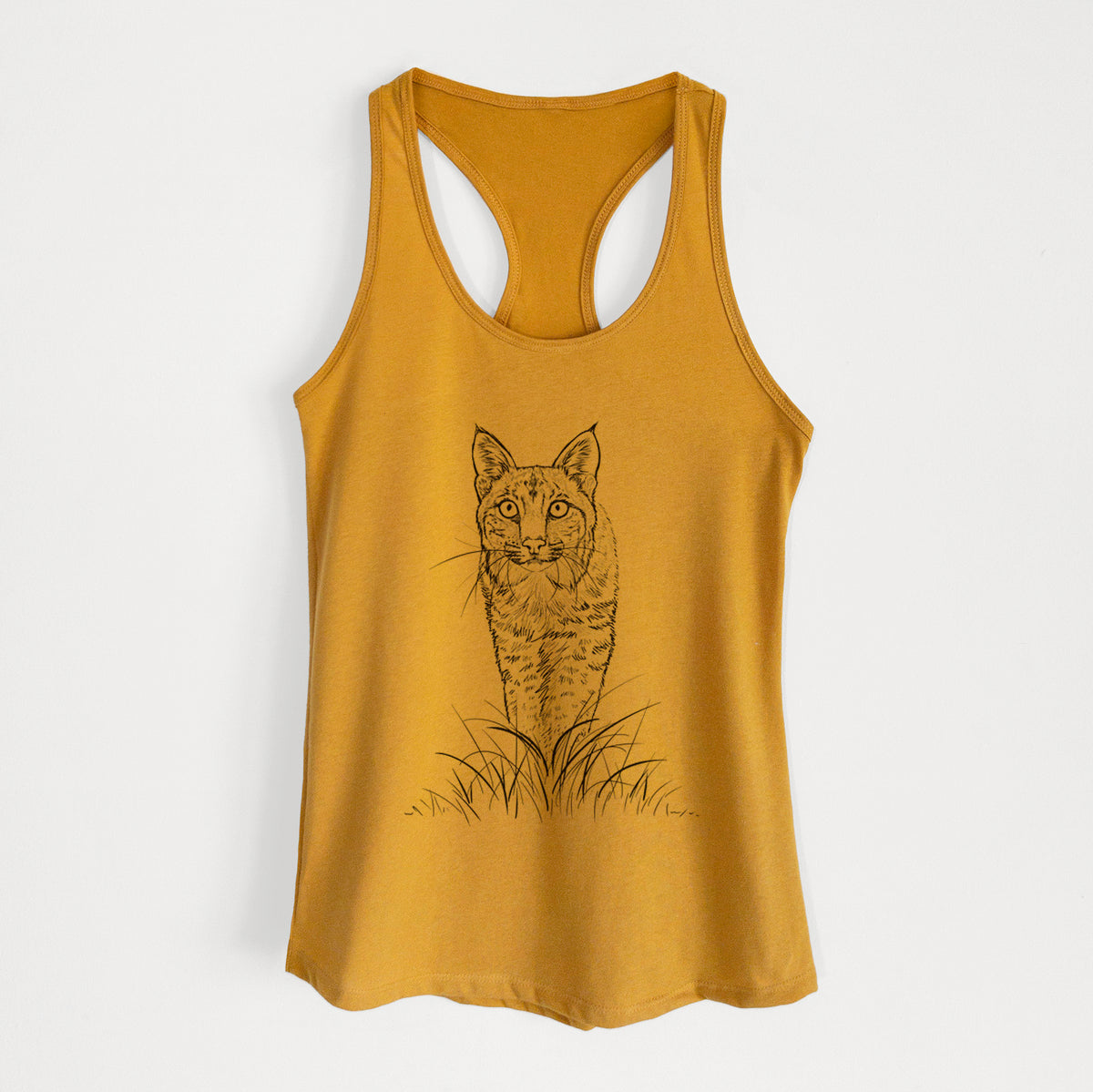 Gold women's racerback tank top laid flat, printed with a black ink illustration of a bobcat standing in tall grass, facing forward.