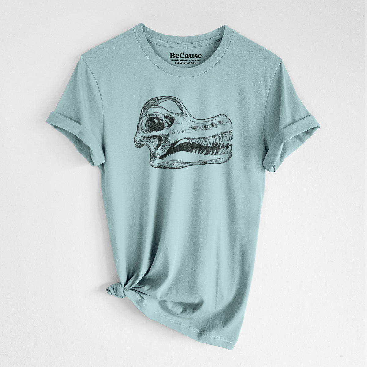 Dusty blue lightweight cotton t-shirt laid flat with the sleeves rolled, printed with a detailed black ink illustration of a Brachiosaurus skull.