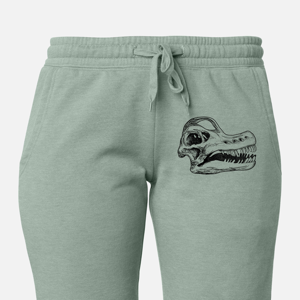 Front of sage green Cali Wave sweatpants, printed with a detailed black ink illustration of a Brachiosaurus skull on the leg.