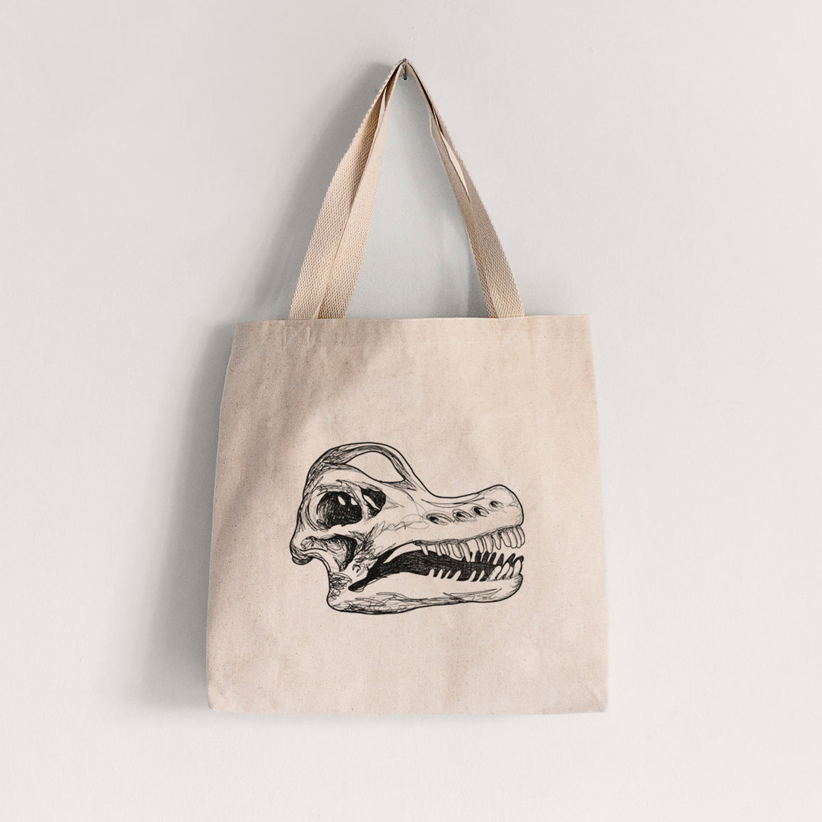 Natural canvas tote bag printed with a detailed black ink illustration of a Brachiosaurus skull.