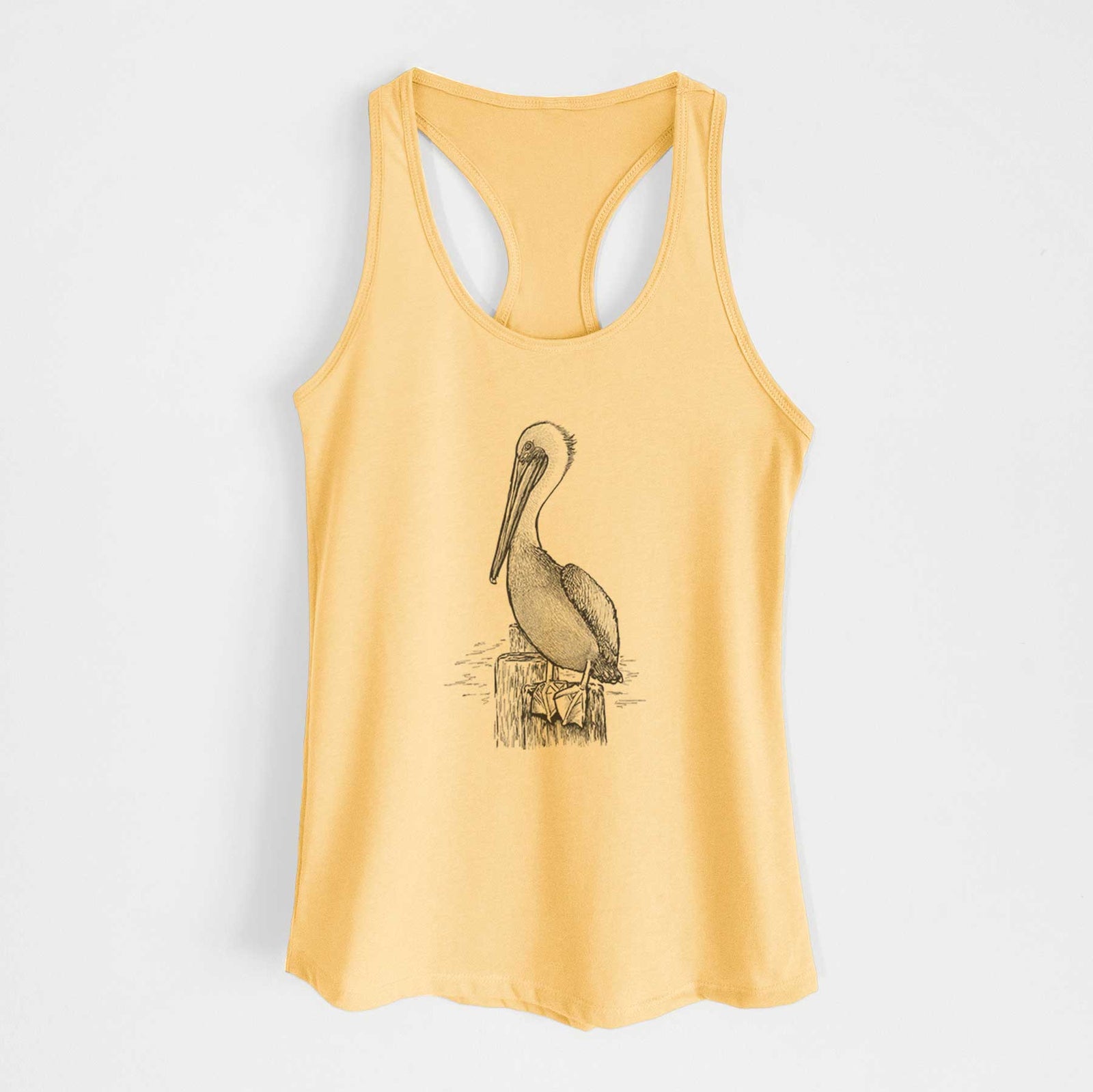Banana cream women's racerback tank top laid flat, printed with a detailed black ink illustration of a brown pelican perched on a wooden piling.