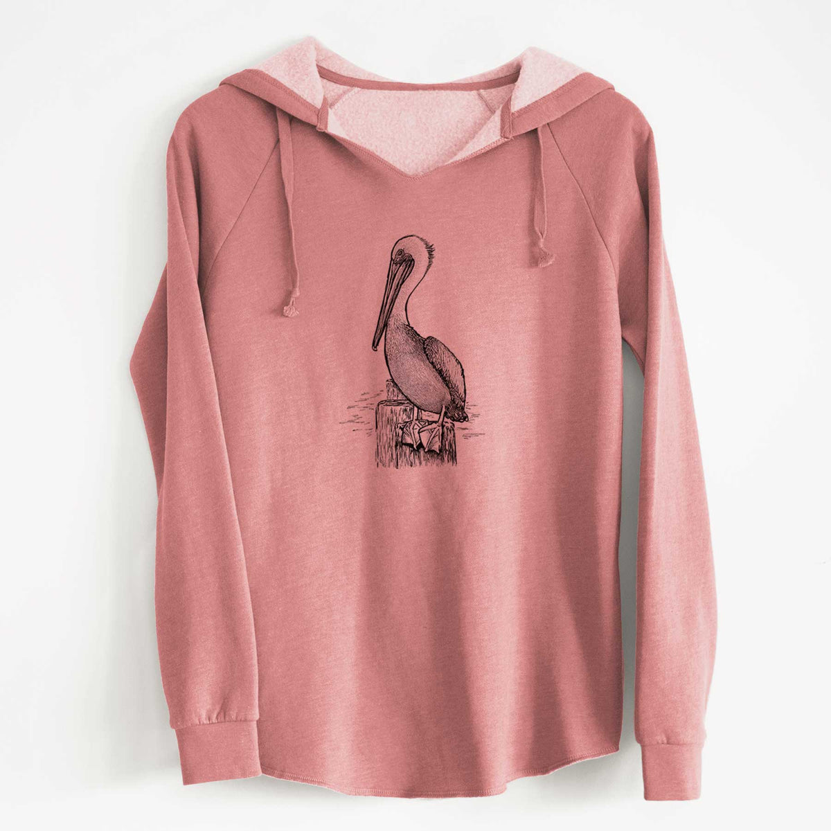 Dusty rose women's Cali Wave hooded sweatshirt laid flat, printed with a detailed black ink illustration of a brown pelican perched on a wooden piling.
