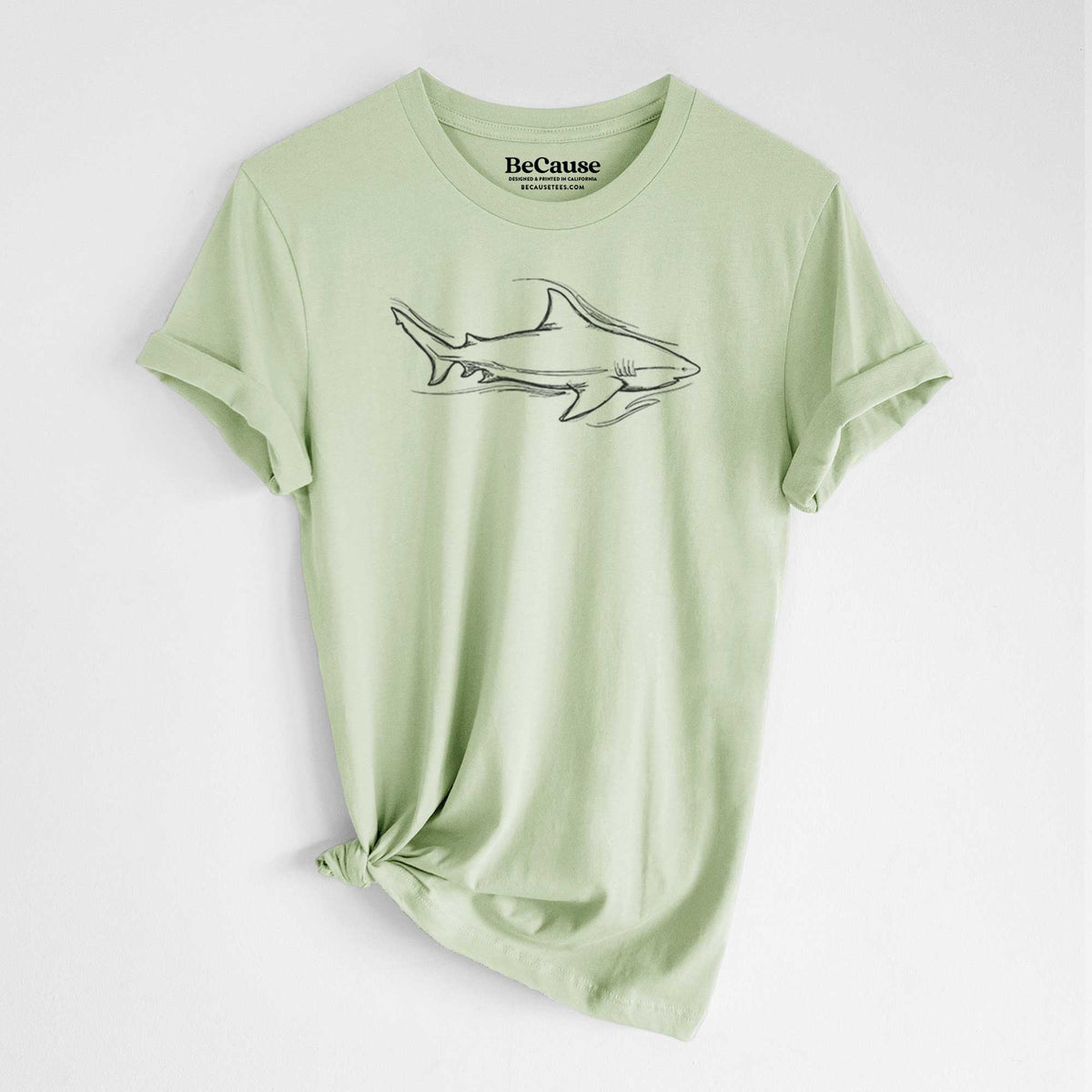 Spring green lightweight cotton t-shirt laid flat with the sleeves rolled, printed with a black ink illustration of a bull shark swimming.