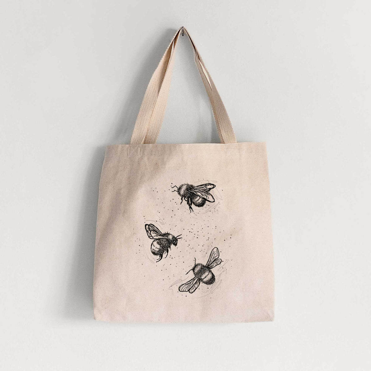 Natural canvas tote bag printed with a black ink illustration of three bumble bees flying.