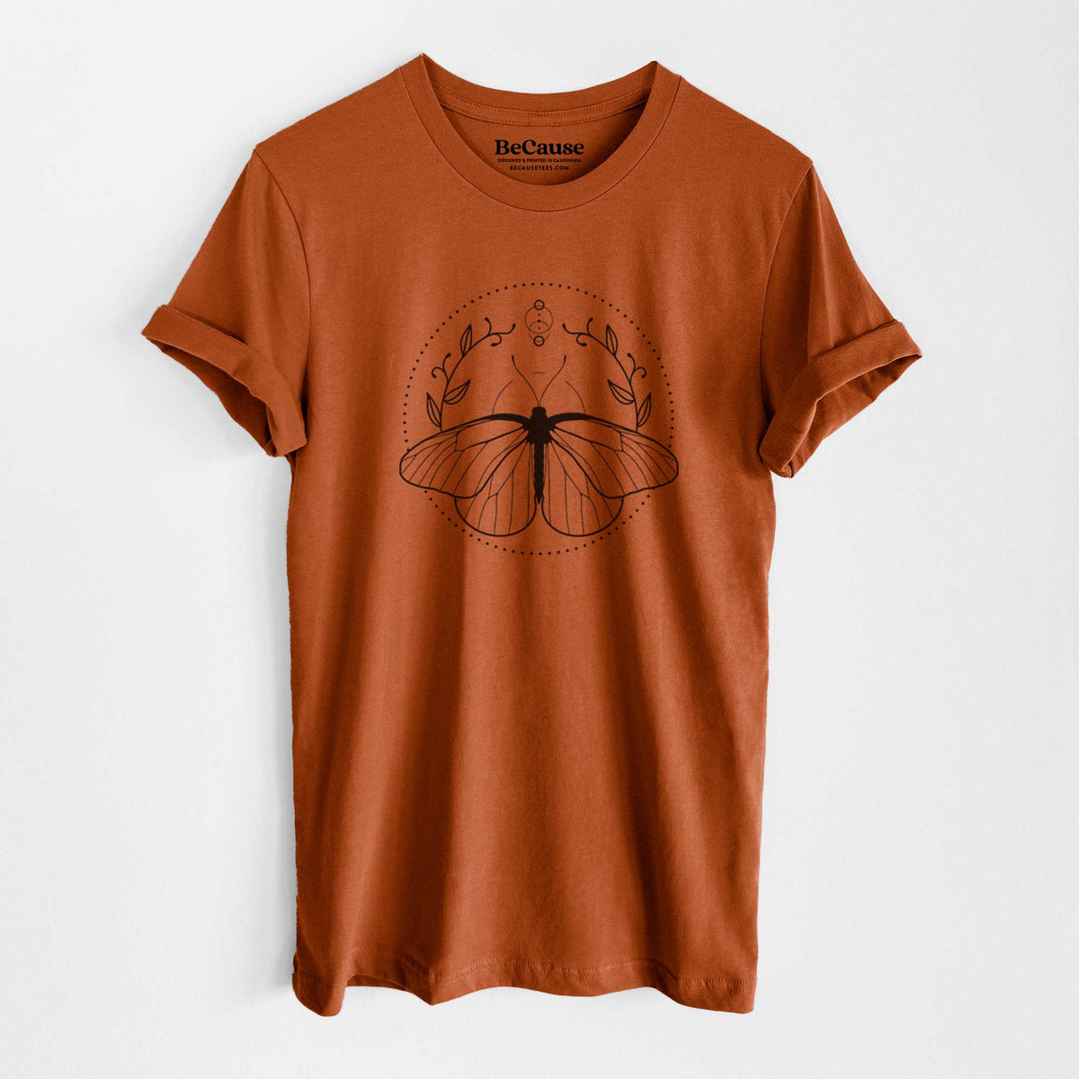 Autumn lightweight cotton t-shirt laid flat, printed with a black ink butterfly inside a circle, framed by moon phases and leaves.