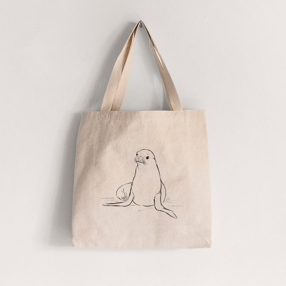 Natural canvas tote bag printed with a black ink illustration of a California sea lion sitting upright.