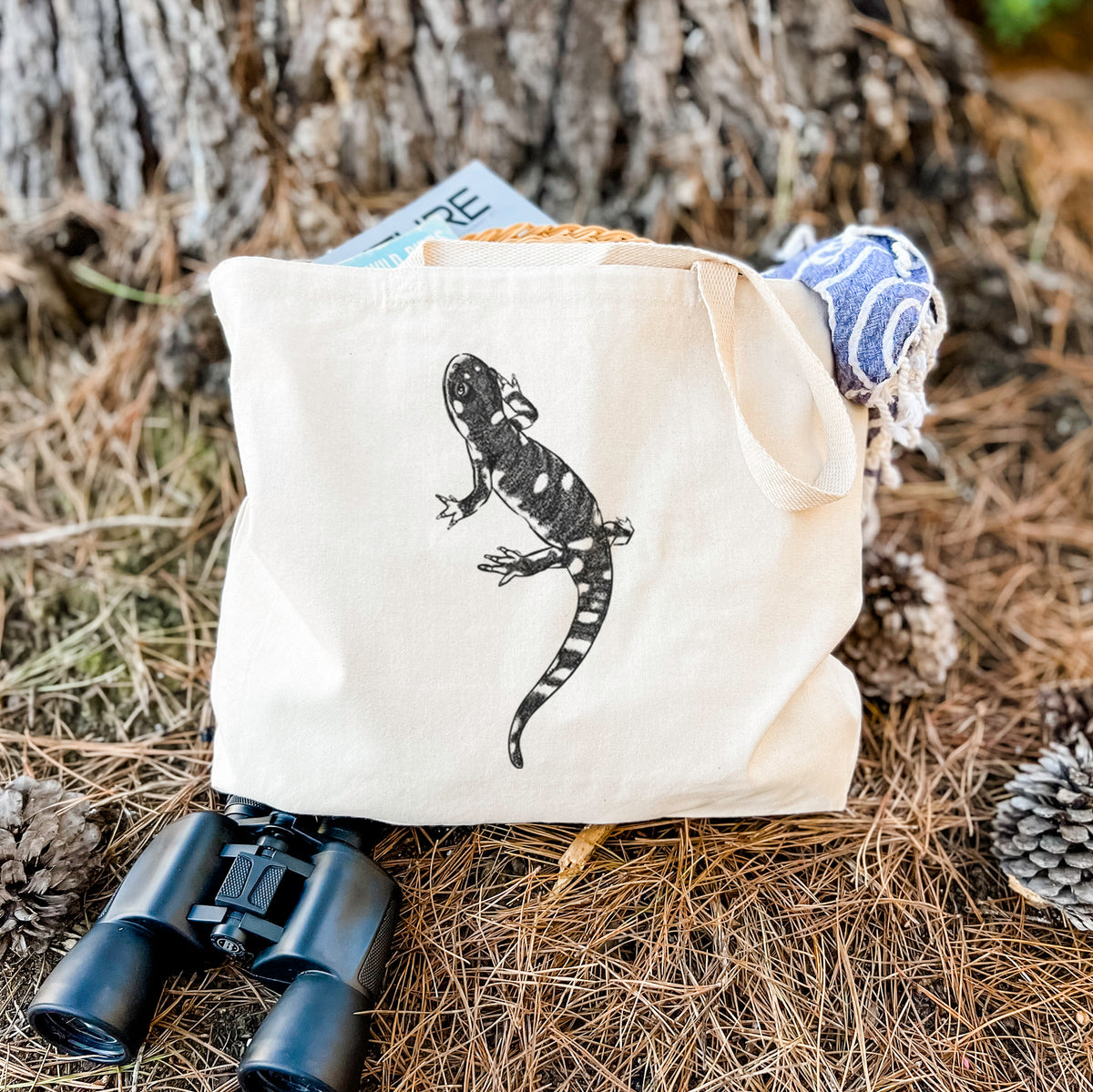Canvas tote bag printed with a detailed black ink illustration of a spotted California tiger salamander, resting on dry grass beside a pair of binoculars.