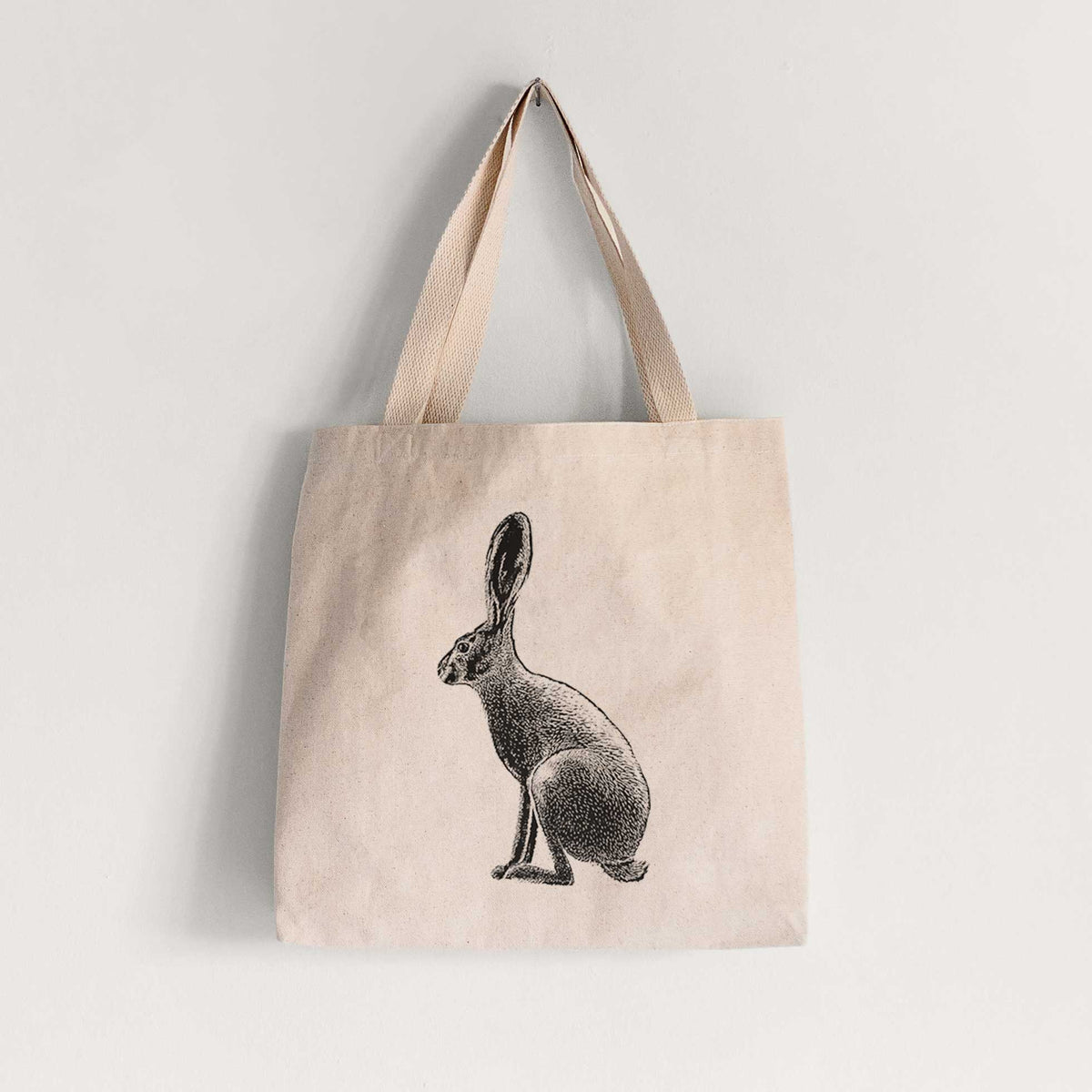 Natural canvas tote bag printed with a detailed black ink illustration of a black-tailed jackrabbit sitting in profile with tall ears.