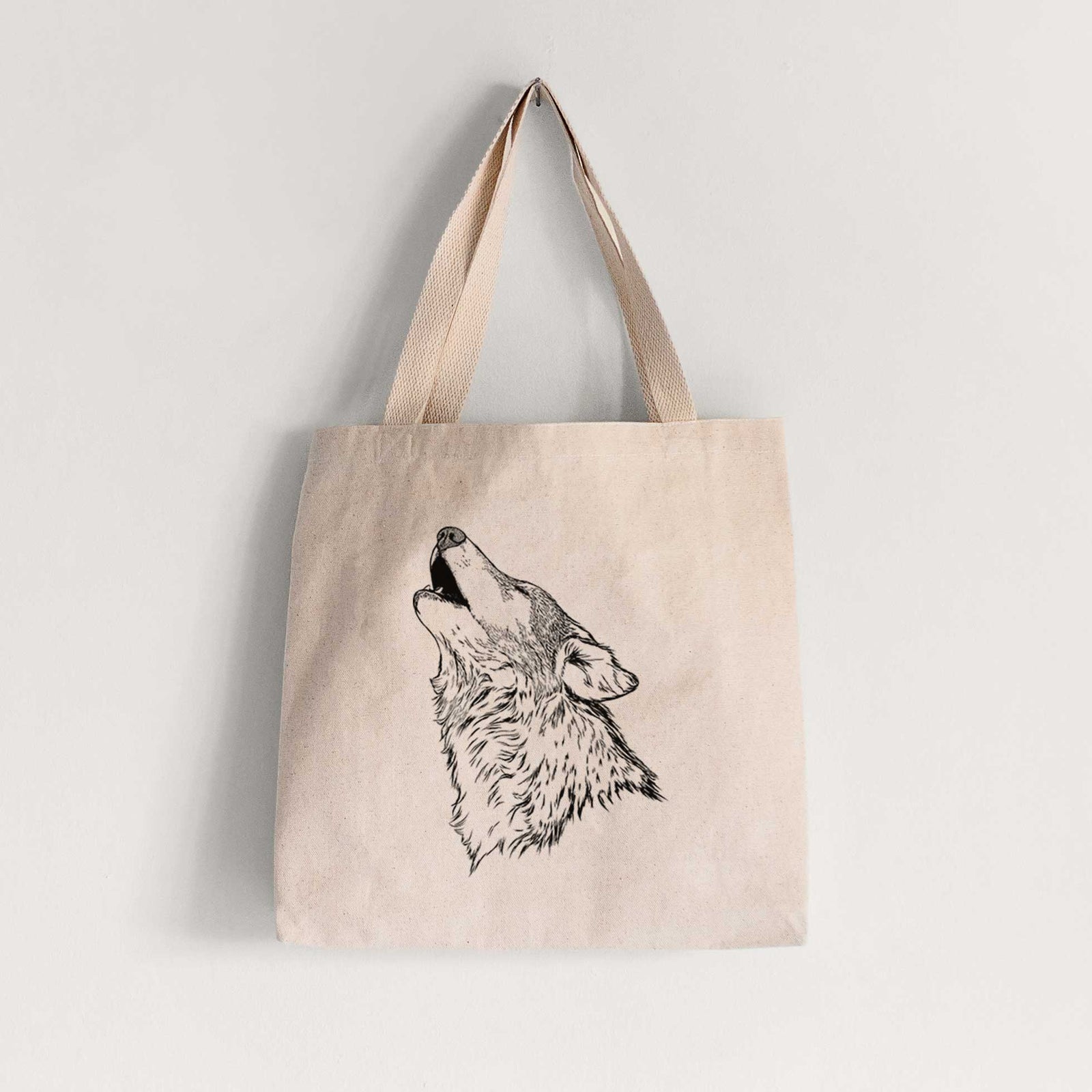 Natural canvas tote bag printed with a detailed black ink illustration of a grey wolf's head and shoulders, howling upward.